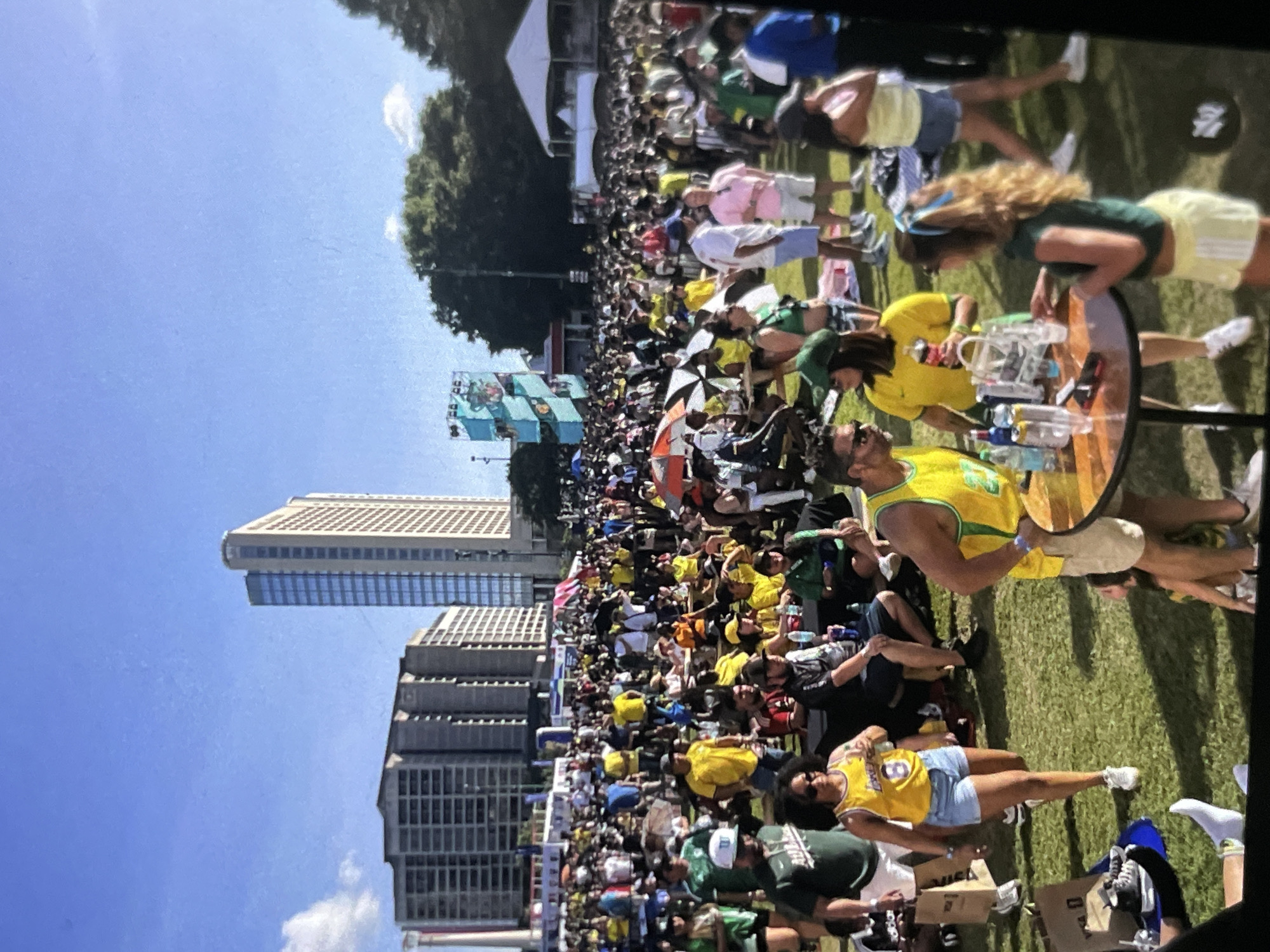 Large crowd gathers in urban park wearing yellow and green
