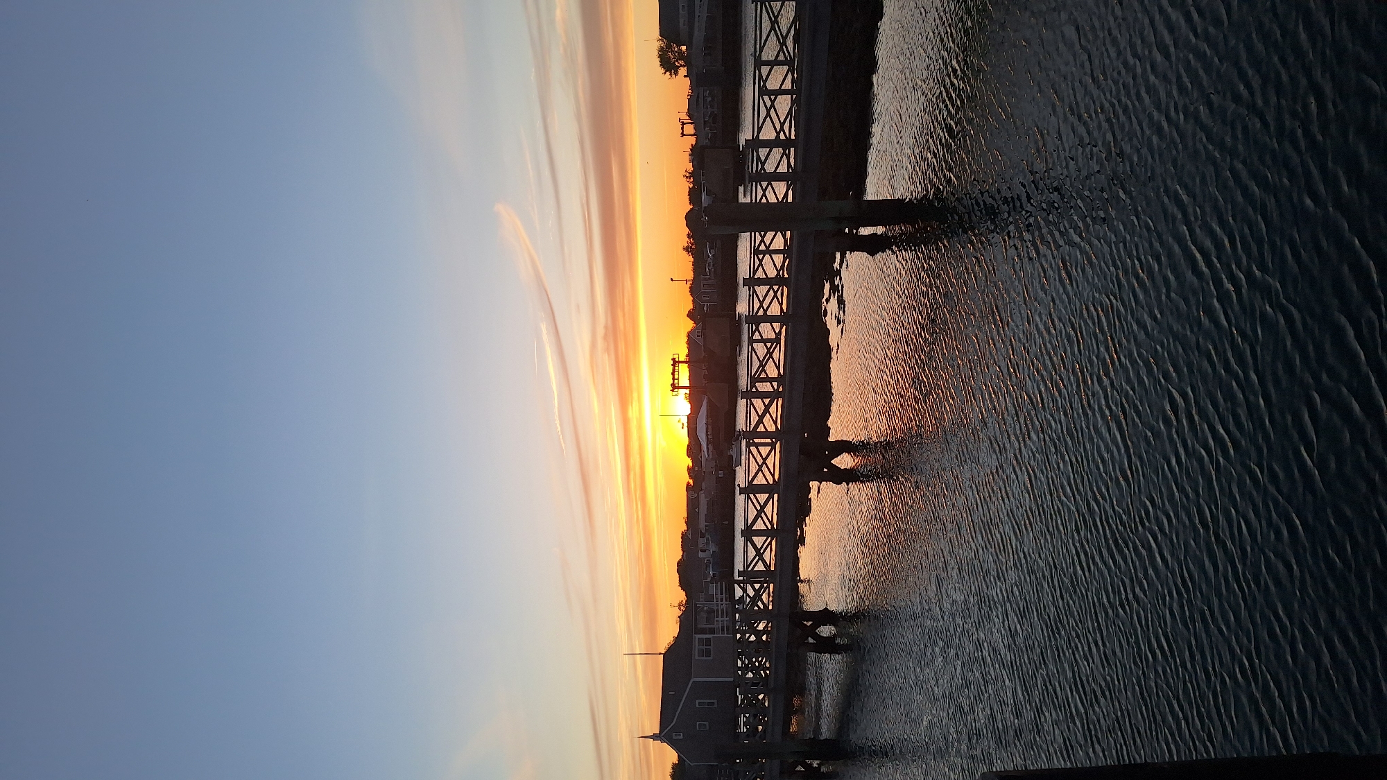 Warm sunset over Nantucket harbor from a wooden boardwalk