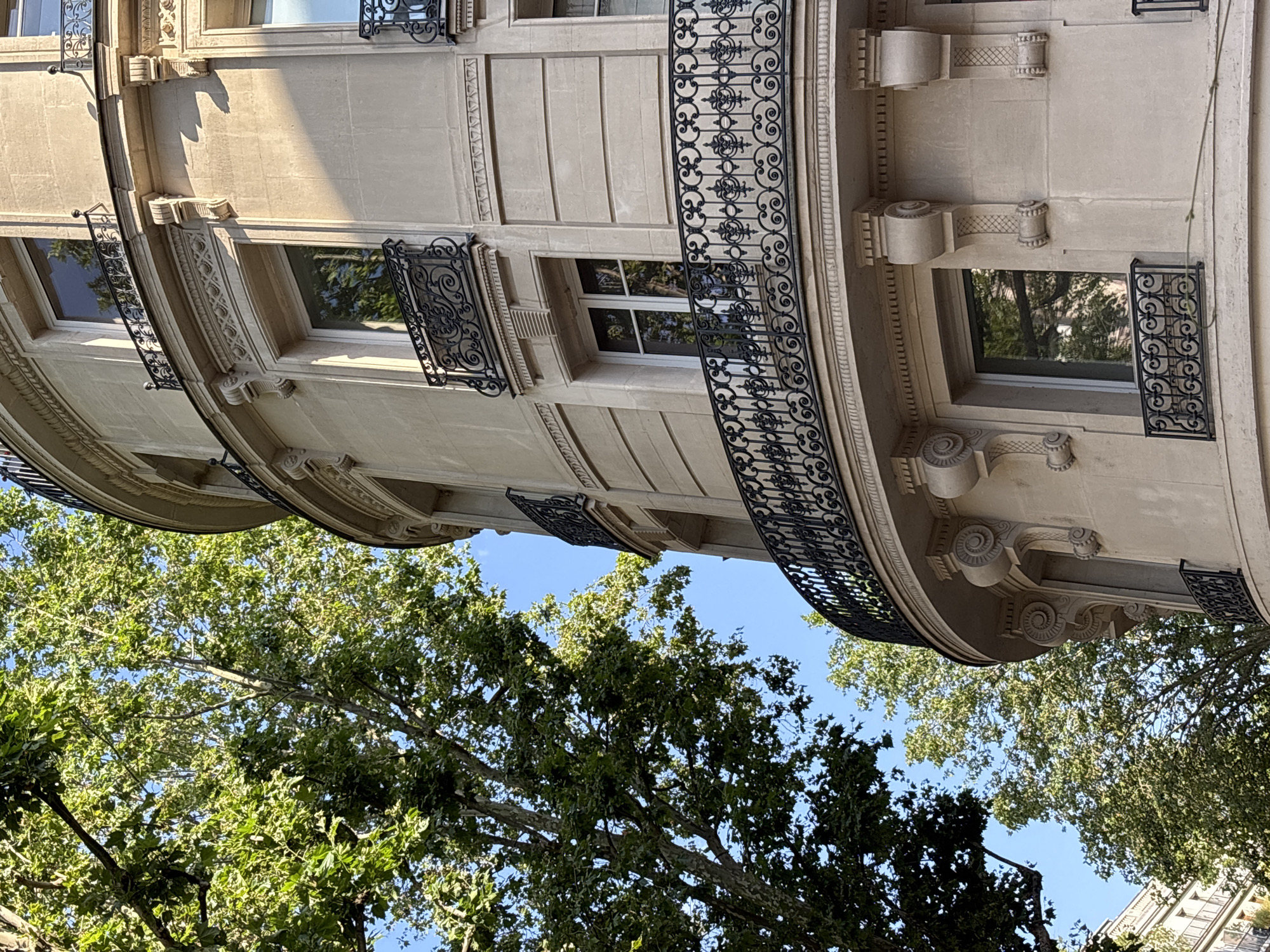 Looking up at an ornate stone building facade in Paris