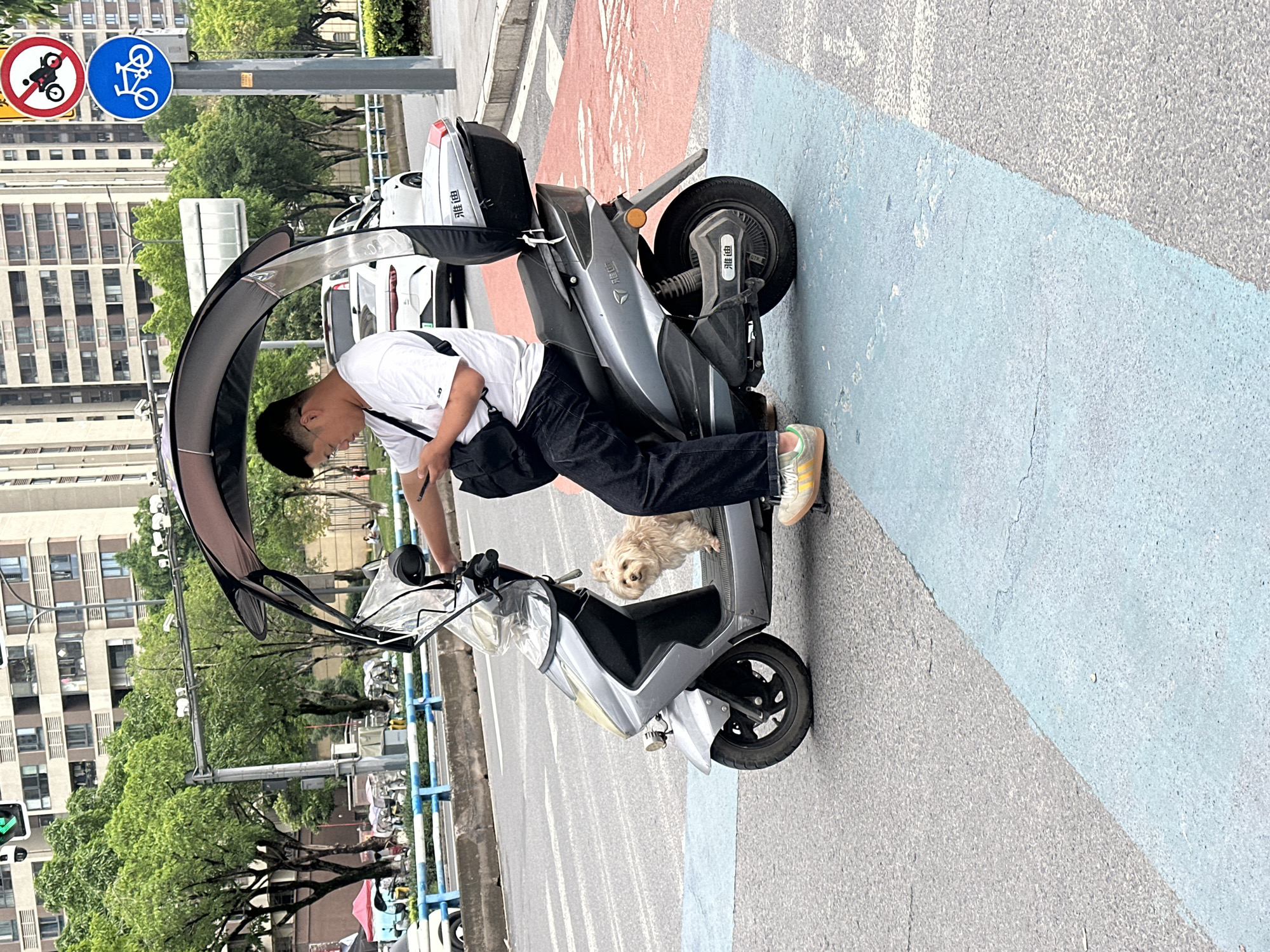 Man with dog pauses on electric scooter in Chongqing