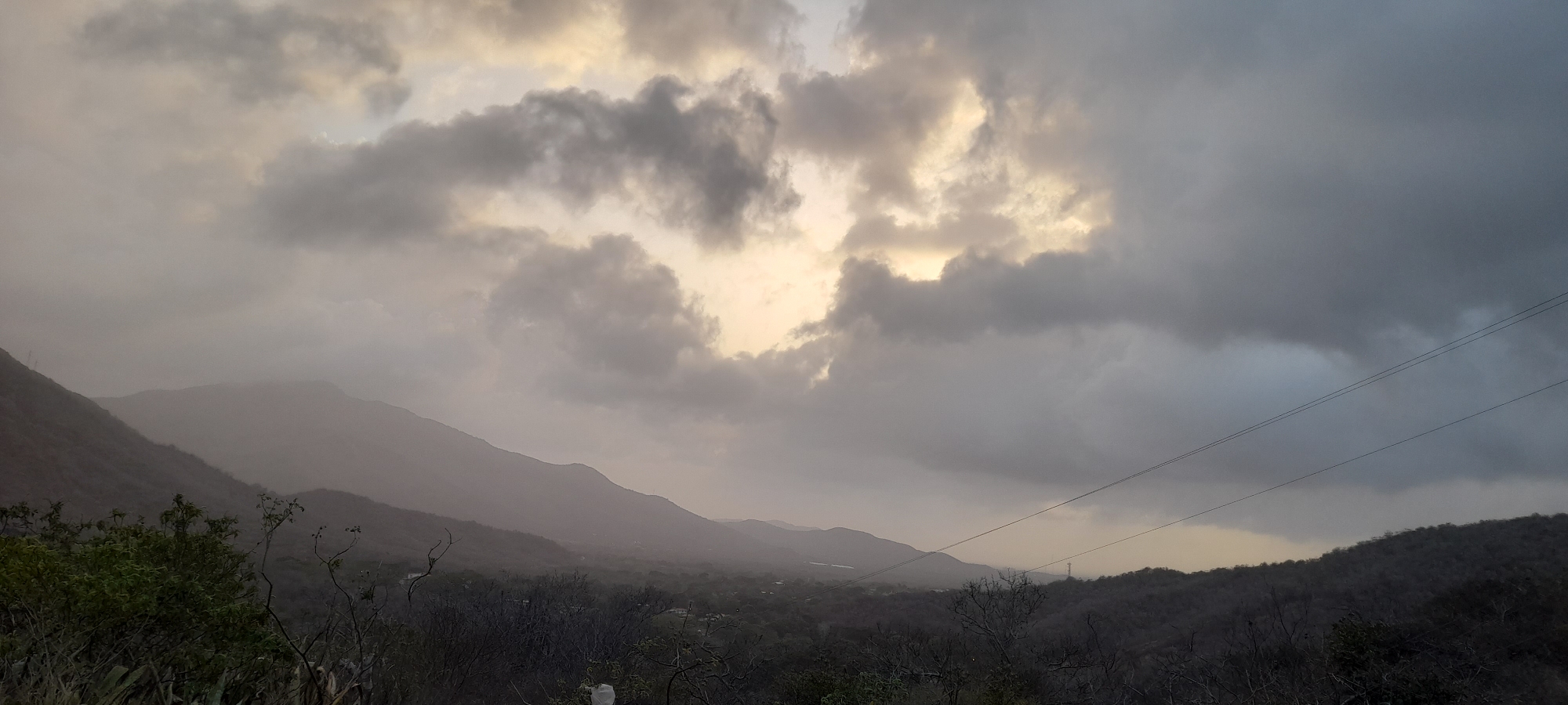 Motorcyclist rides through mountainous terrain under stormy skies