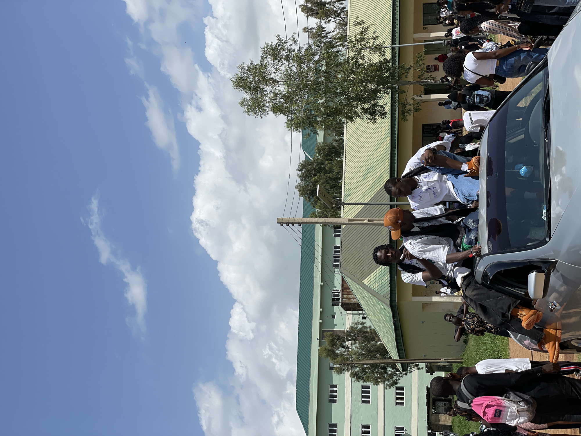 Outdoor celebration gathering around cars on a Nigerian campus
