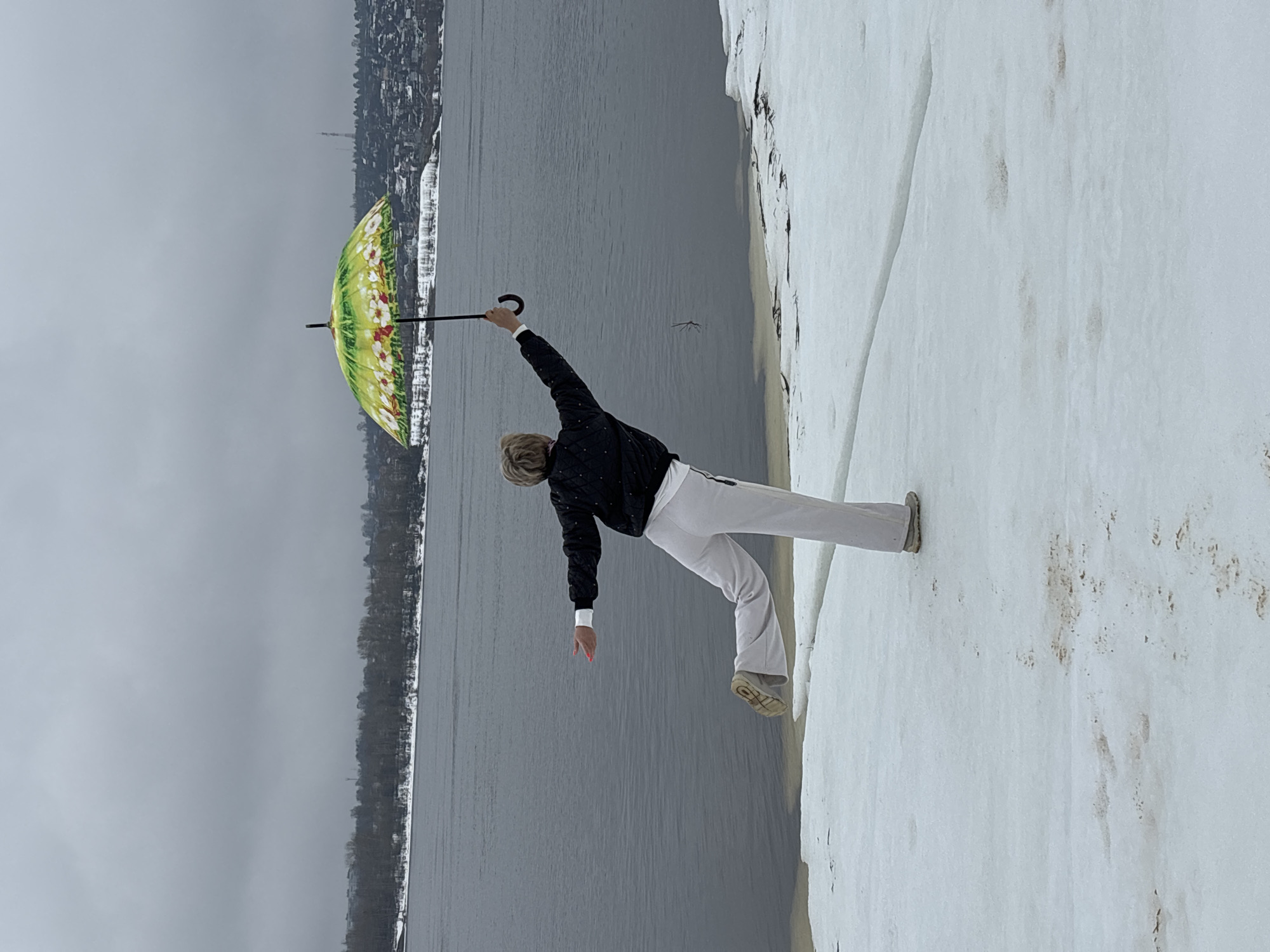 Woman gestures toward water on snowy shore in Chaikovsky