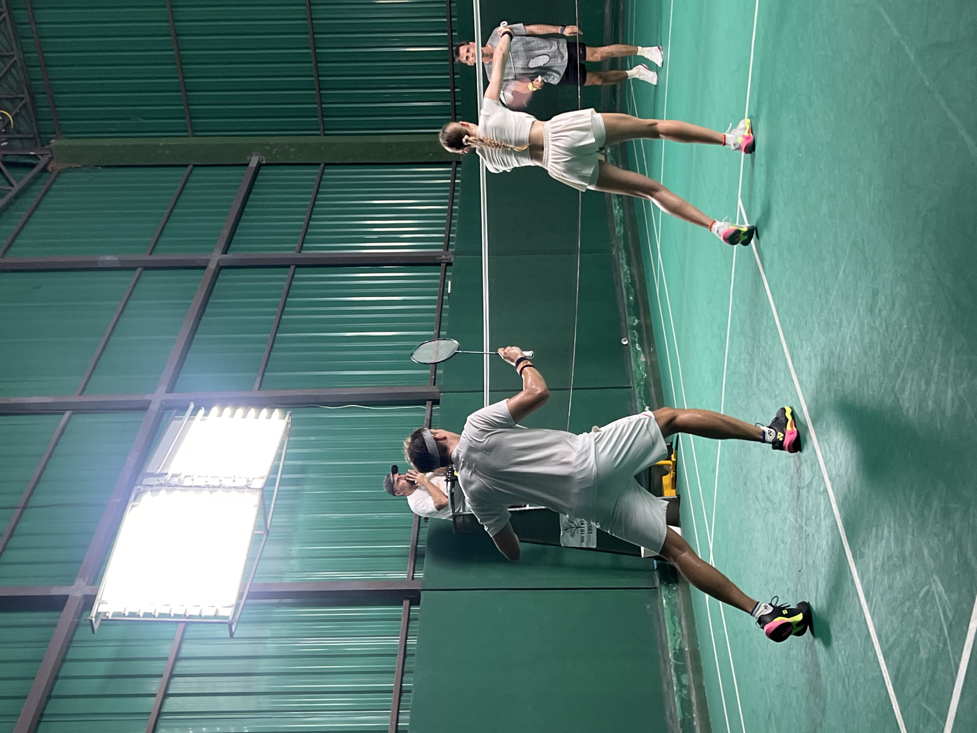 Indoor doubles badminton match captured by multiple witnesses