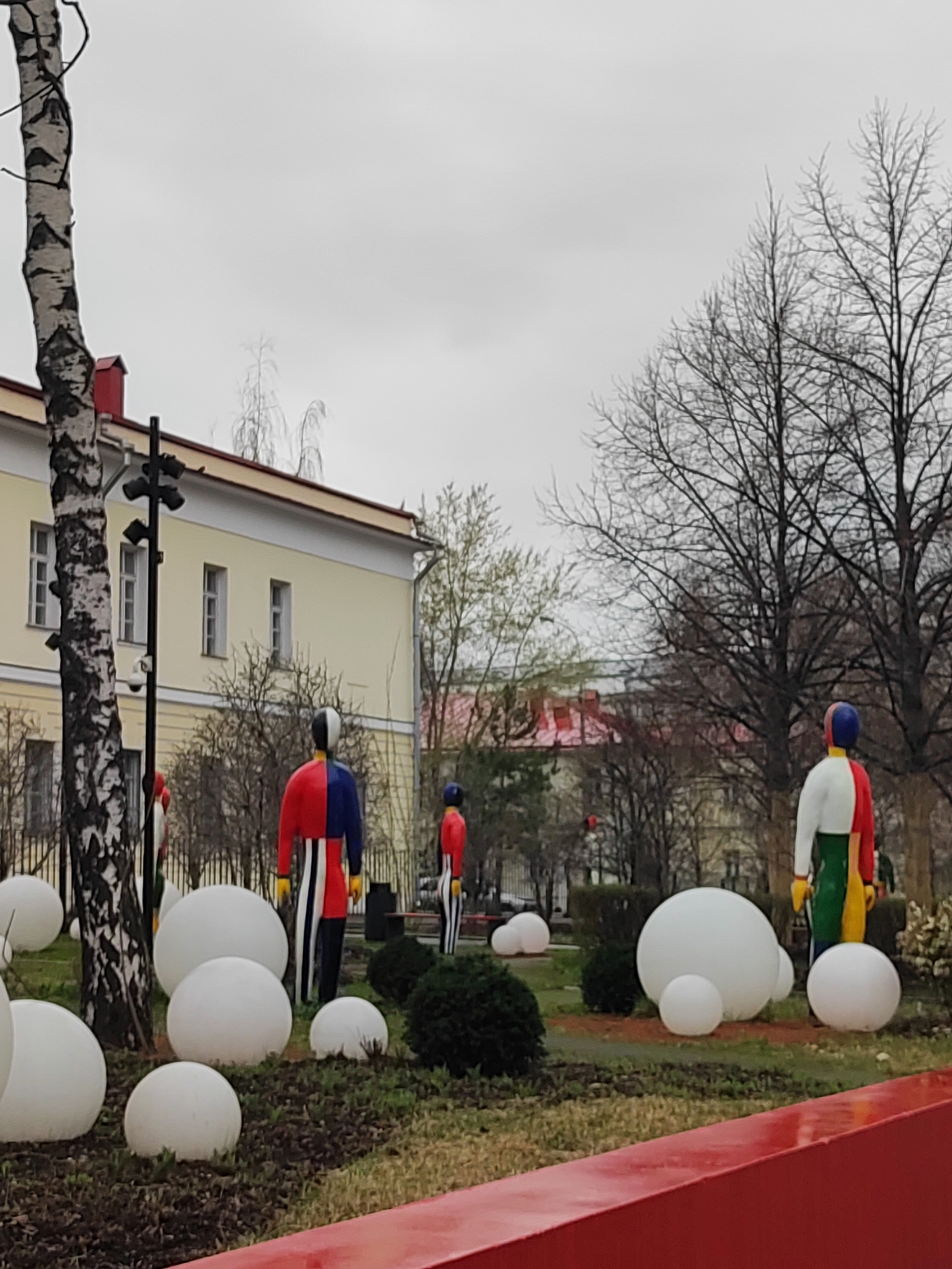 Art installation with white spheres, human sculptures observed in urban park