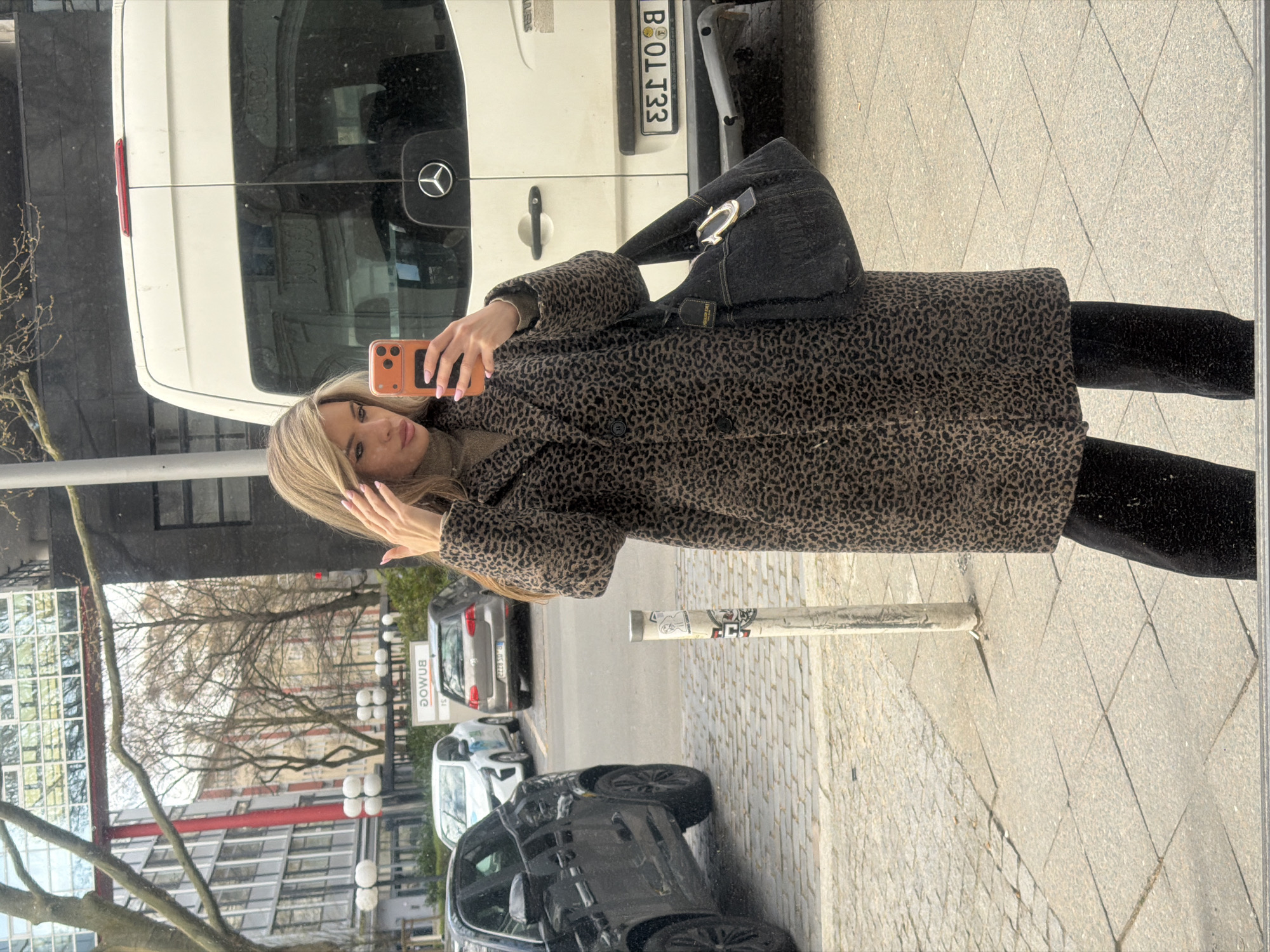 Woman takes selfie on Berlin street near Mercedes van