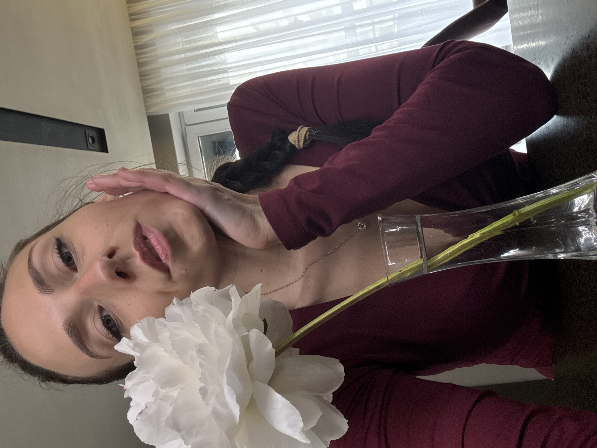 Woman poses with flower near wine display in Saint Petersburg