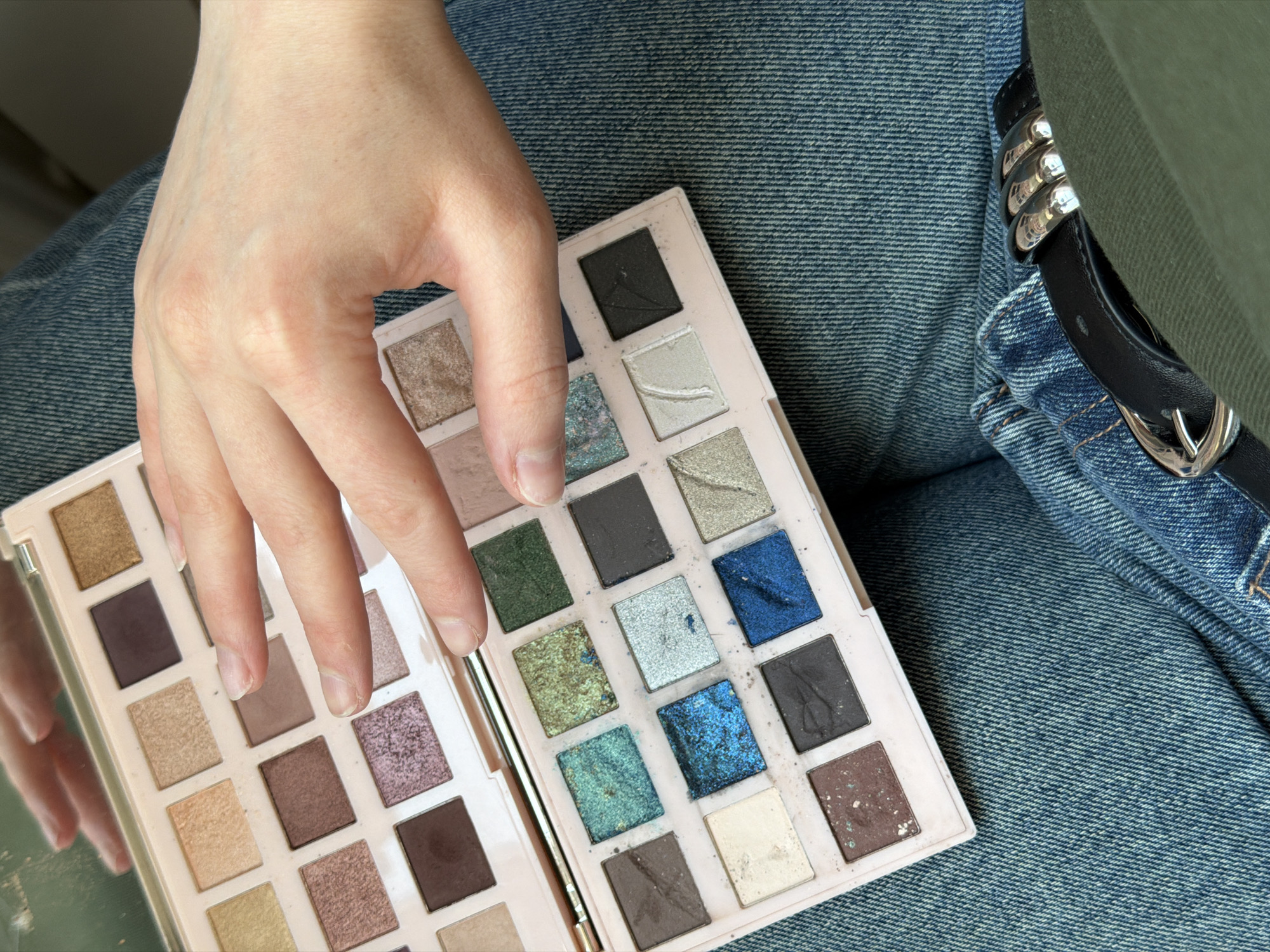 Person applies makeup using colorful eyeshadow palette in Russia