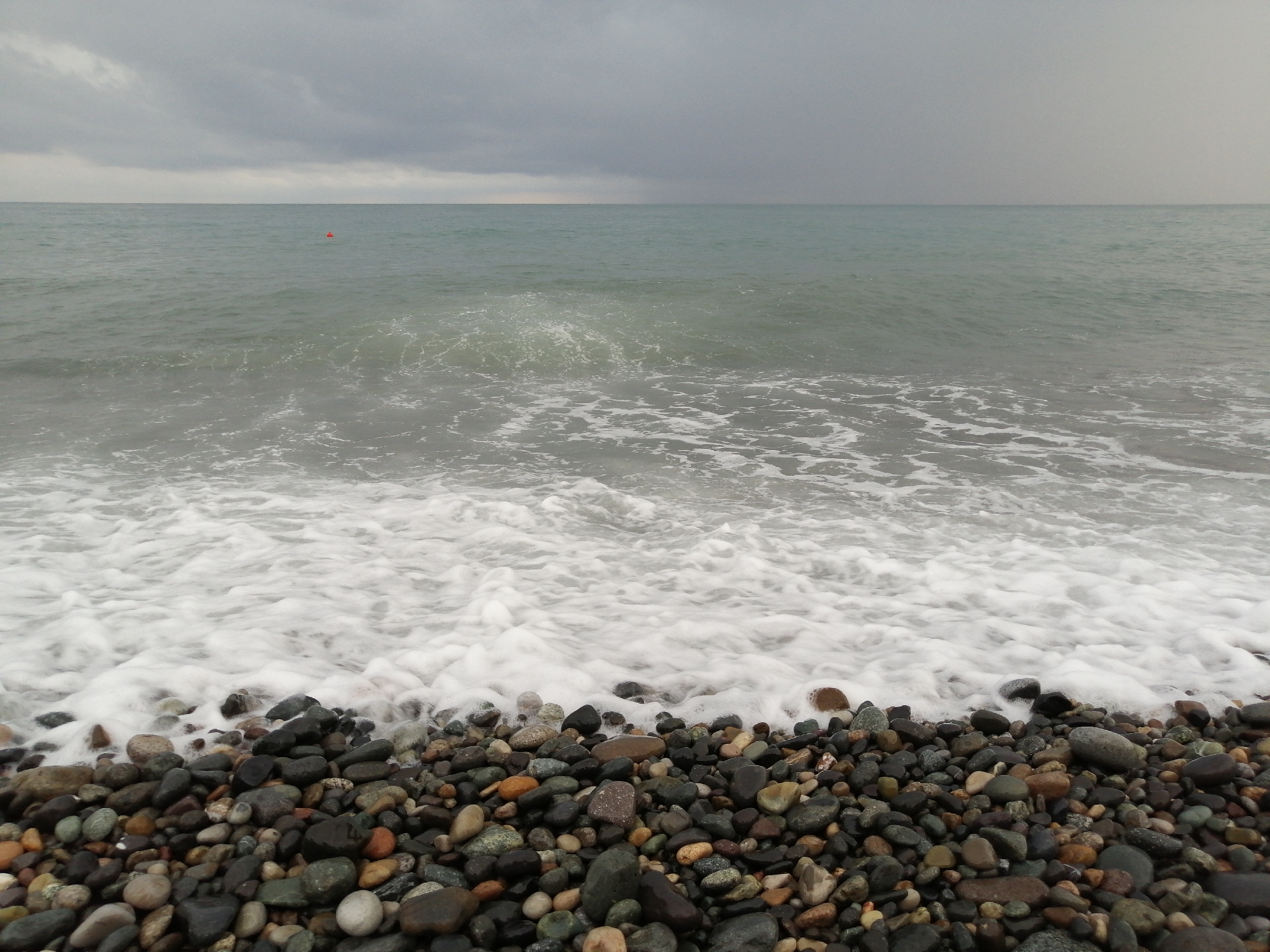 Batumi's pebble beach and seafront path on a grey morning