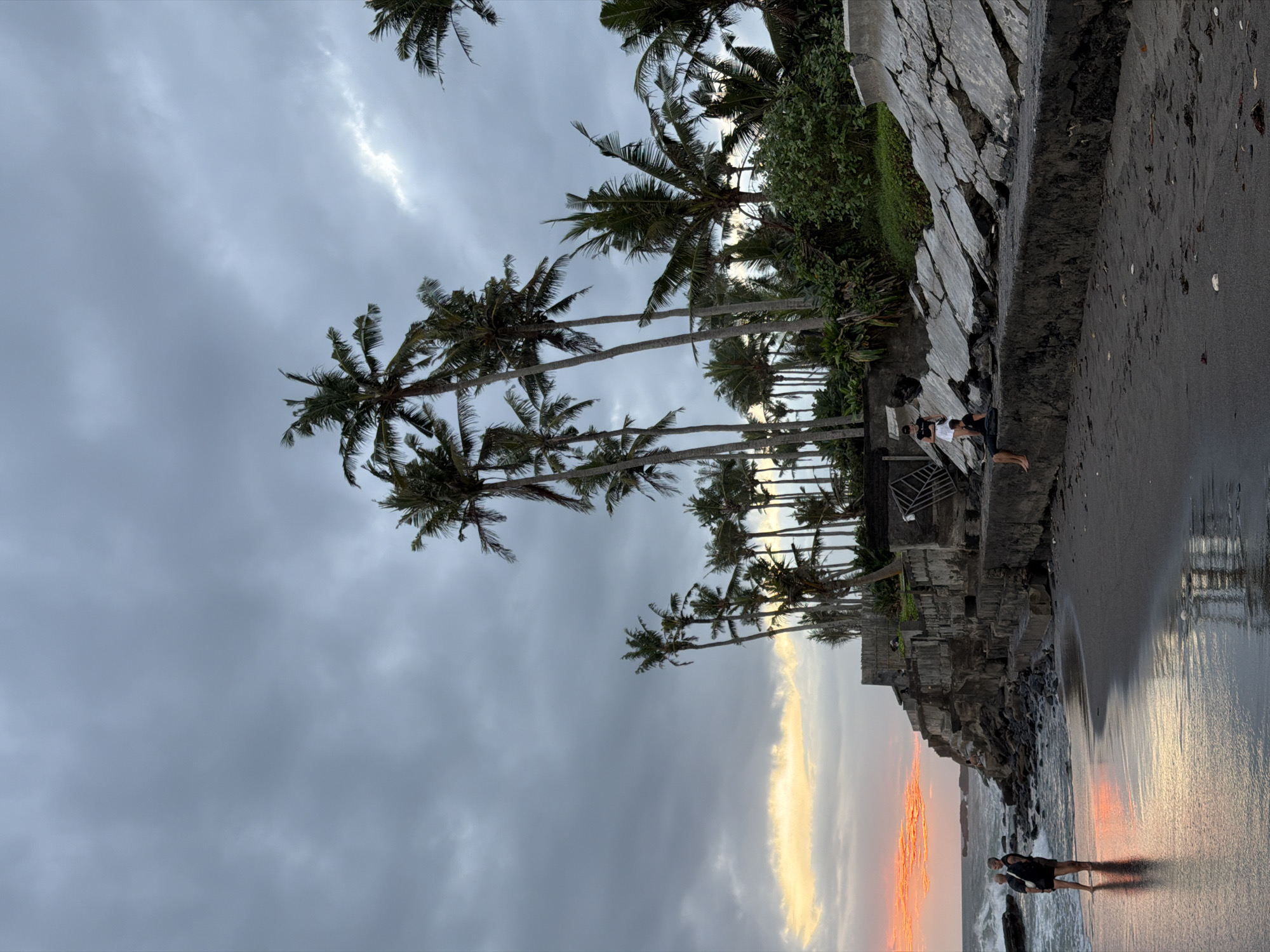 Beach life continues under dramatic sunset skies in Mengwi