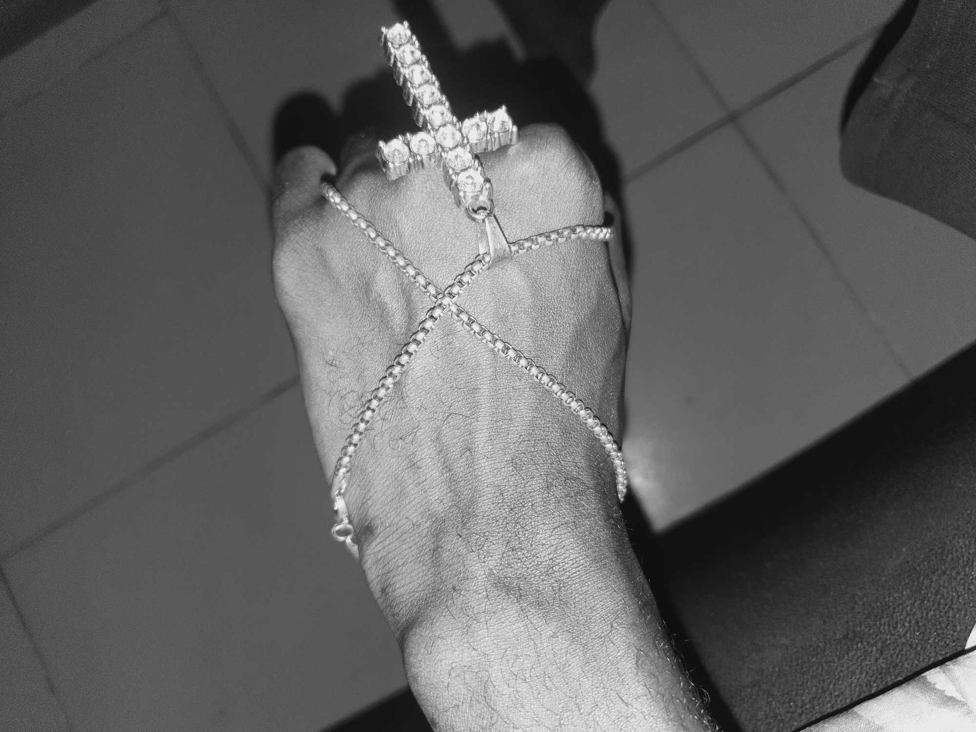 Person displays cross jewelry in artistic photo session in Lokoja