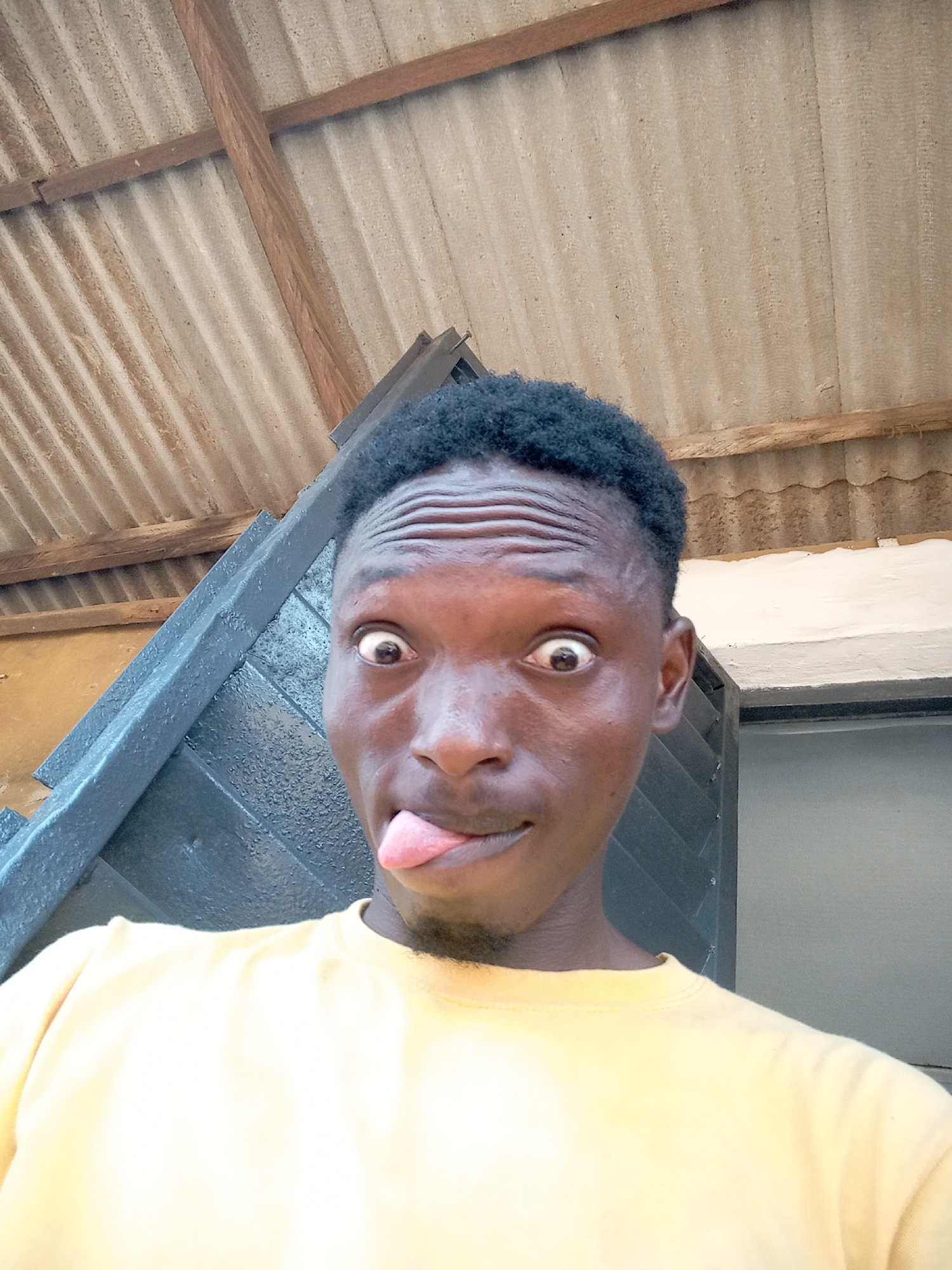 Man takes playful selfies in rural setting with motorcycle, goat