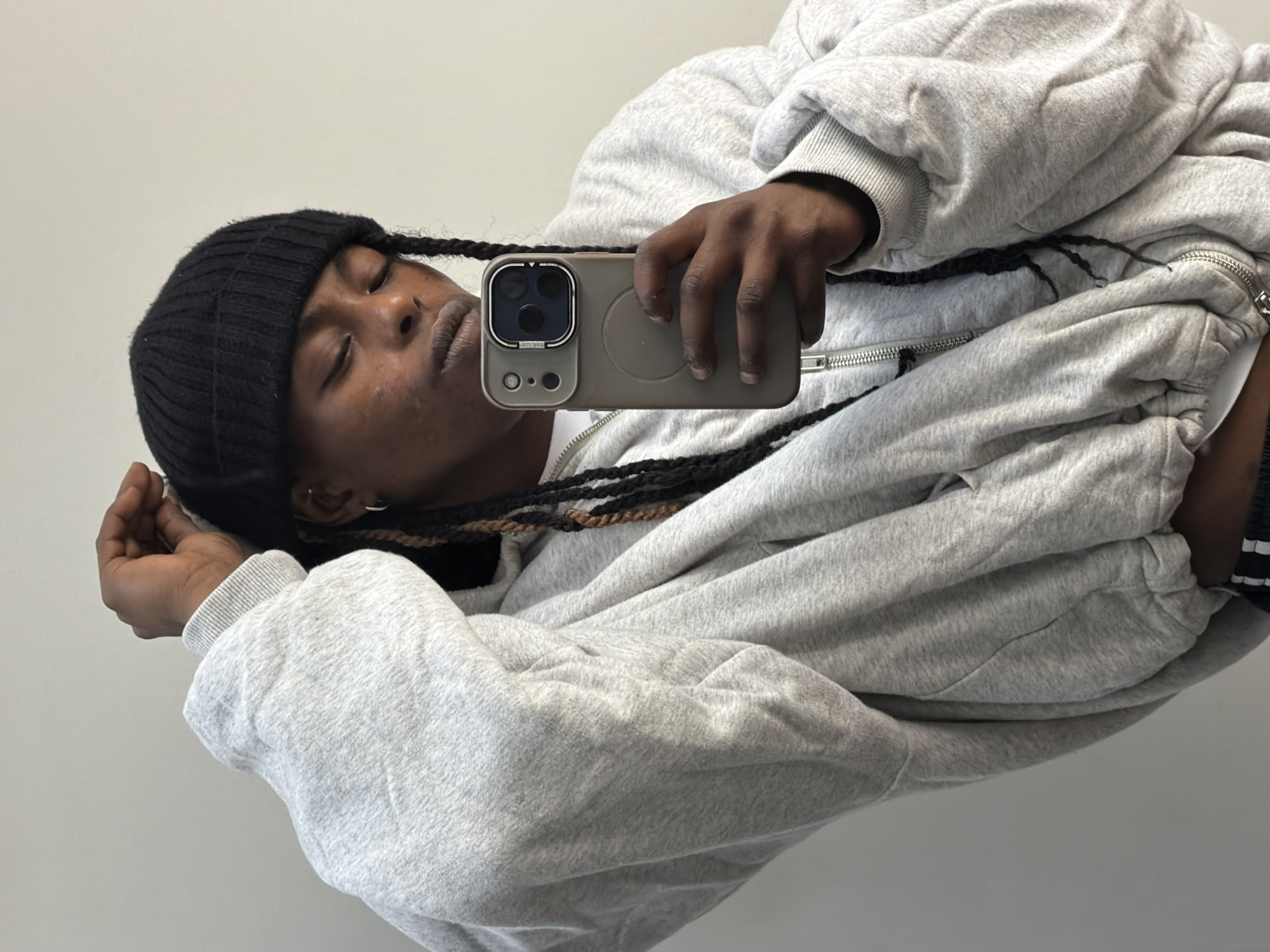 Person takes selfie in grey hoodie against wall in London