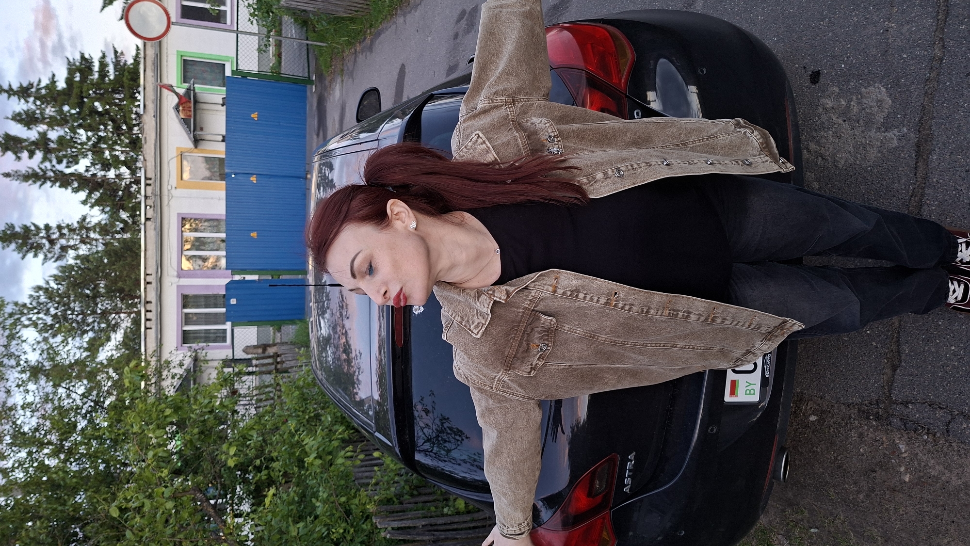 Woman lies on car hood during twilight in Belarus