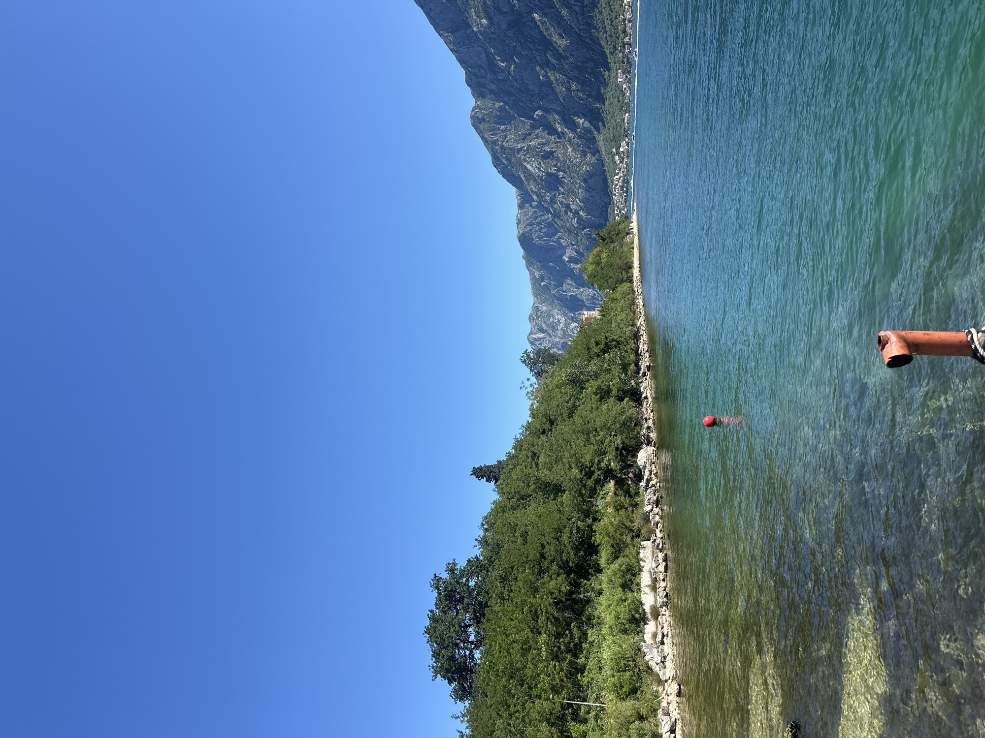 Morning sunlight illuminates Dobrota coastline with red buoy present