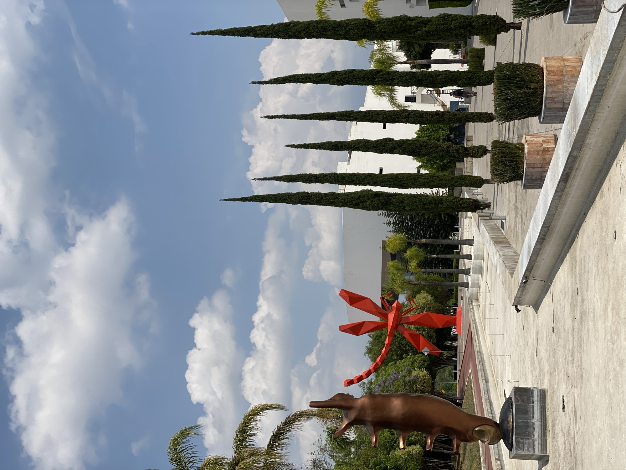 Metallic bovine sculpture observed alongside red geometric structure