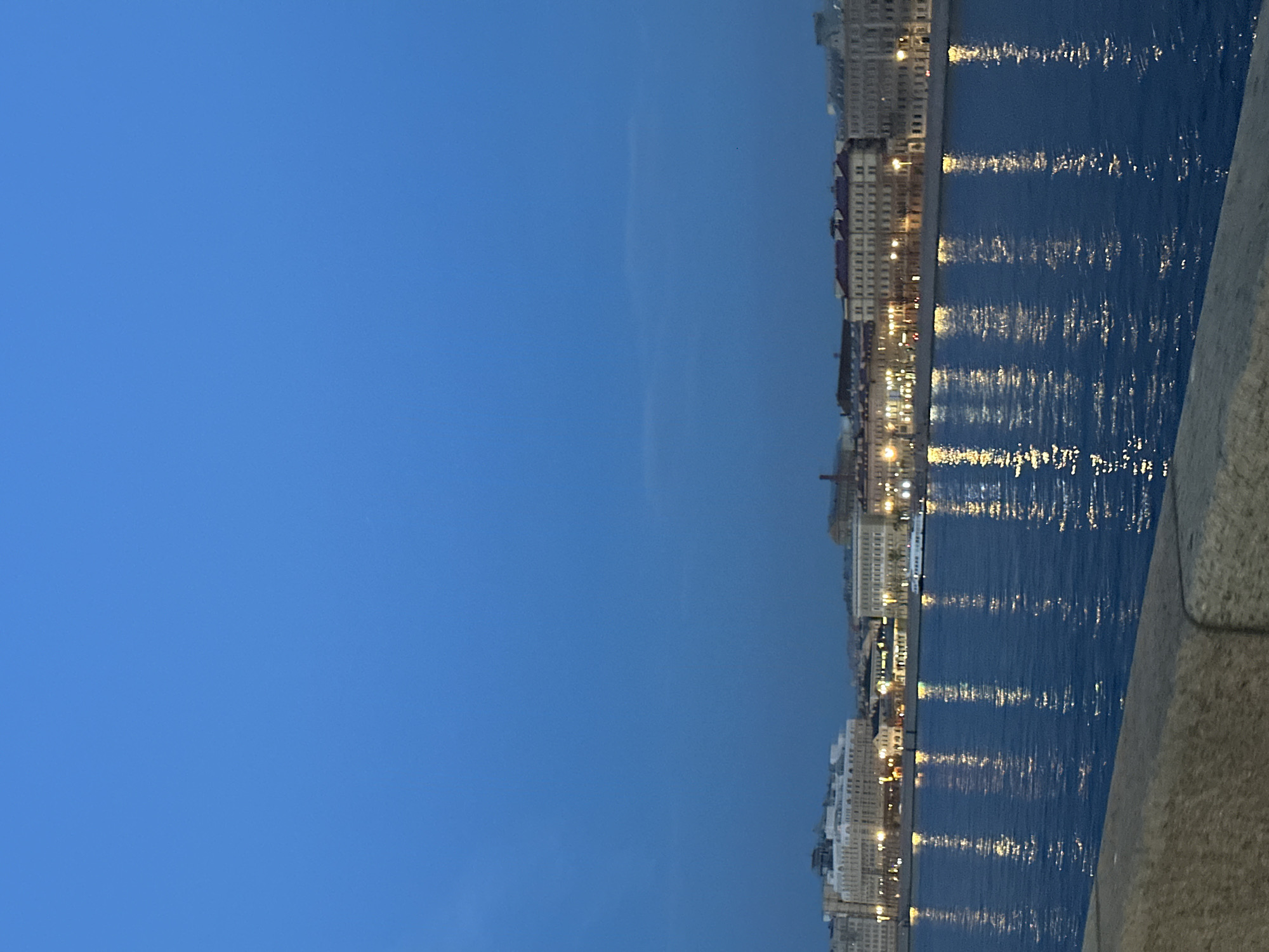 Dusk waterfront cityscape observed with reflective river lights
