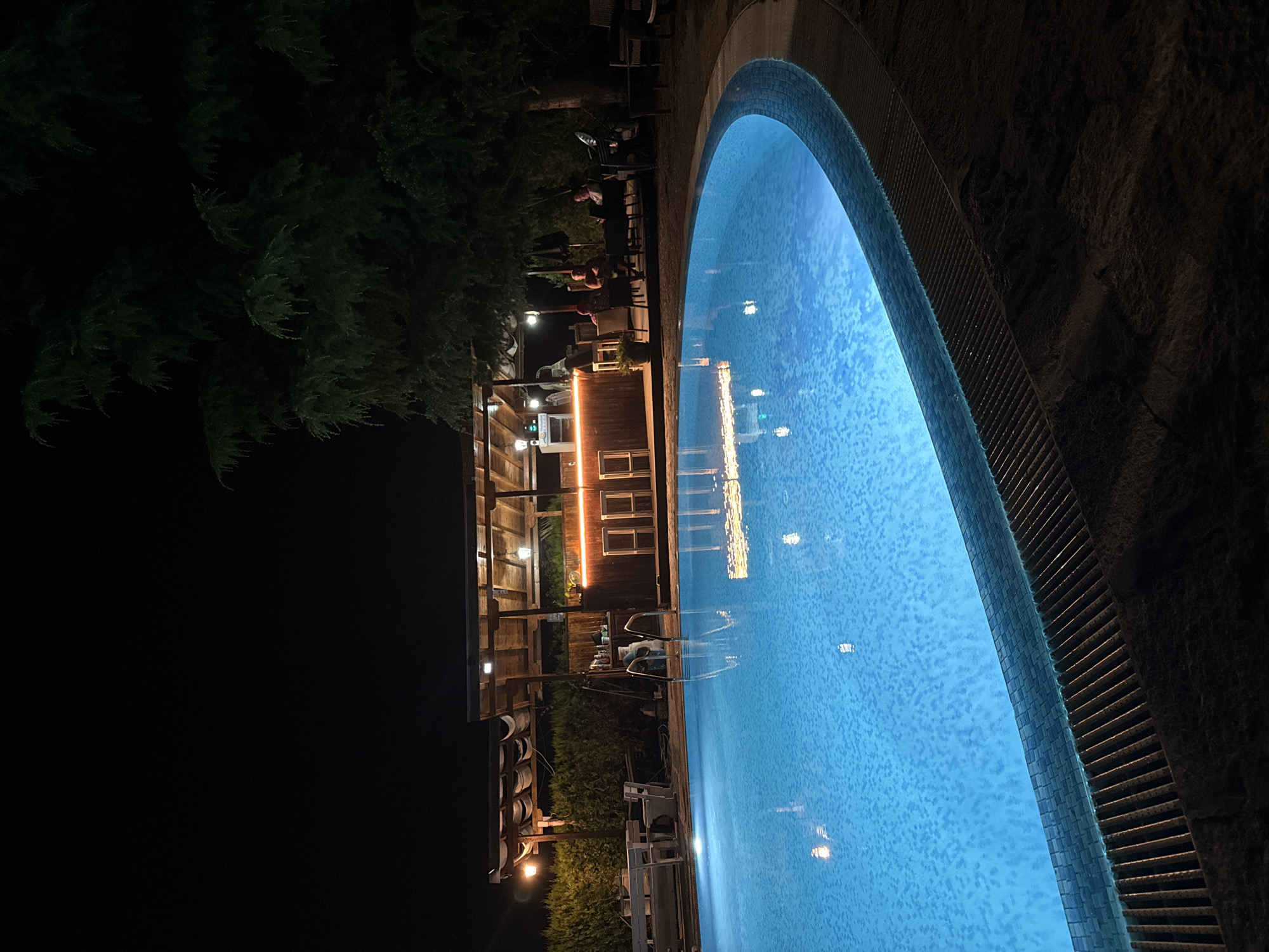 Blue-lit pool beside an outdoor bar in Ravda at night