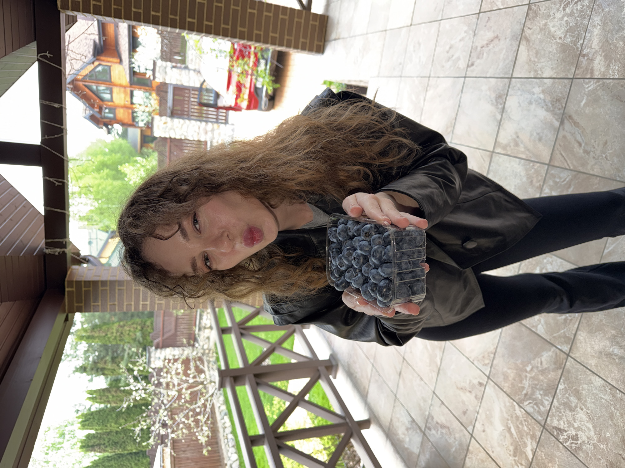 Woman holds blueberry container on porch in Новоглаголево