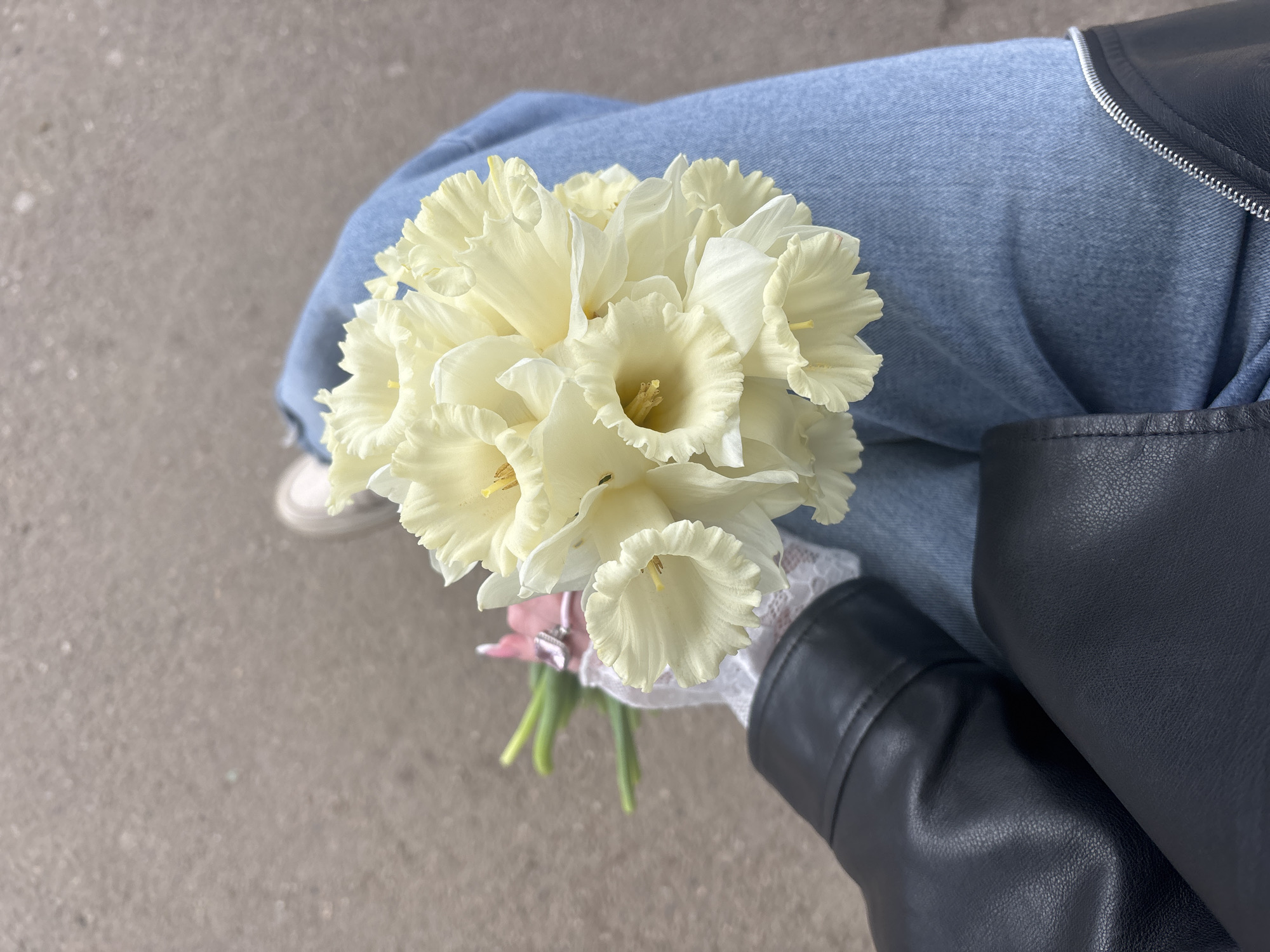 Person with daffodil bouquet sits on Krasnodar sidewalk