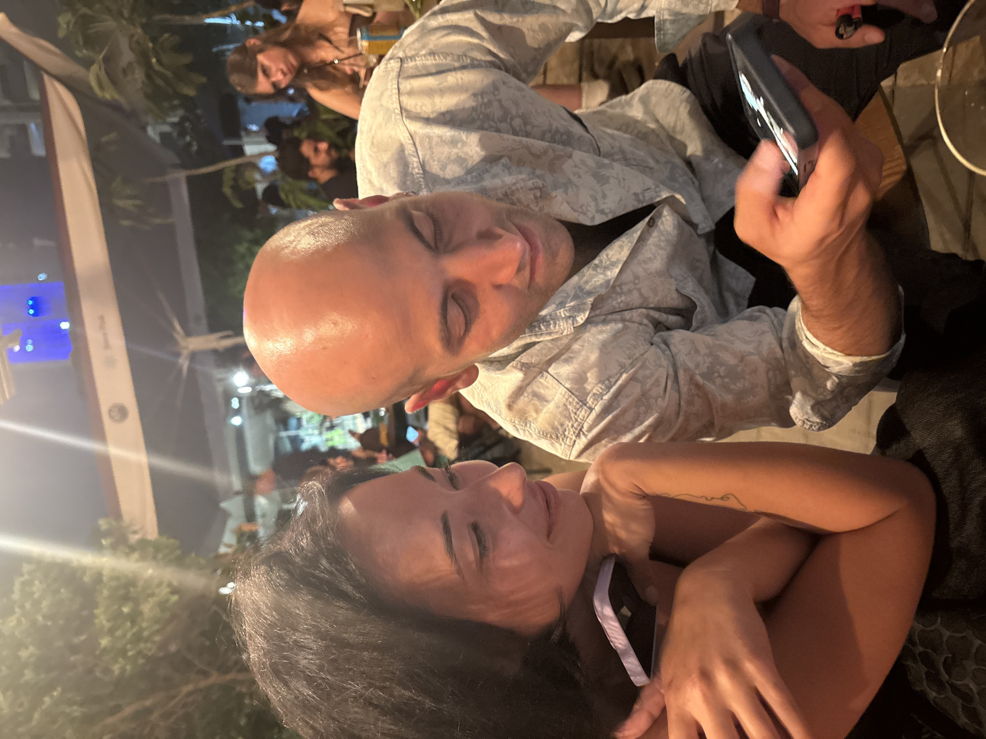 Outdoor café table, Tel Aviv — phone check mid-conversation