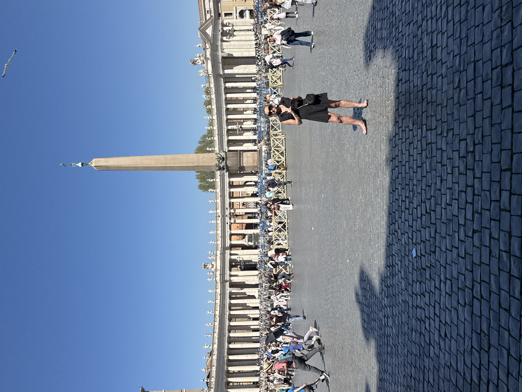Crowd gathers at St. Peter's Square with umbrellas, large screen