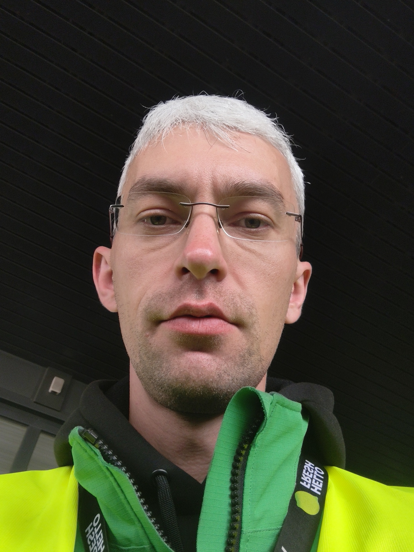 Close-up selfie with glasses, black hoodie, and yellow accent