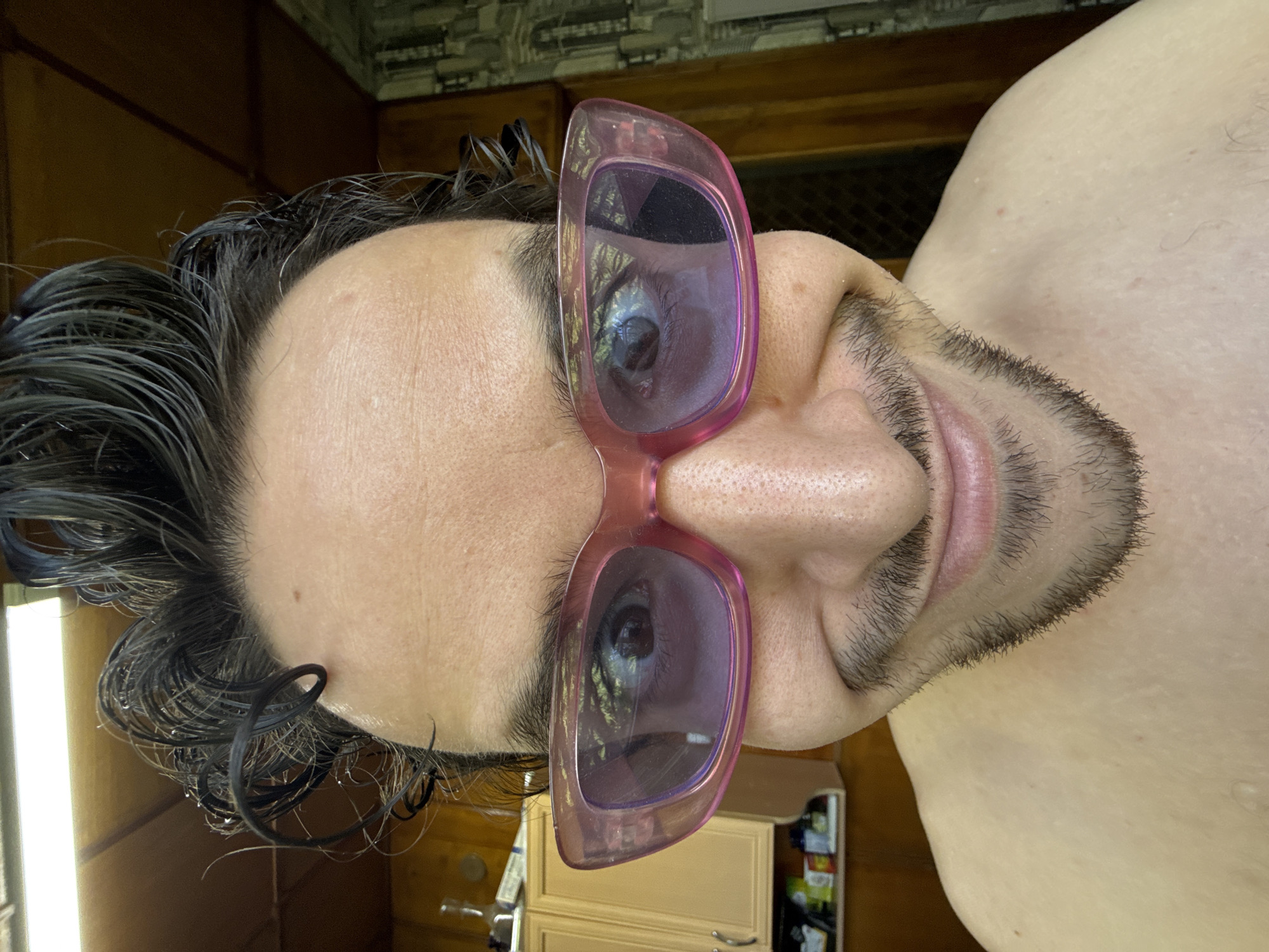 Man tries on multiple sunglasses indoors in Tashkent