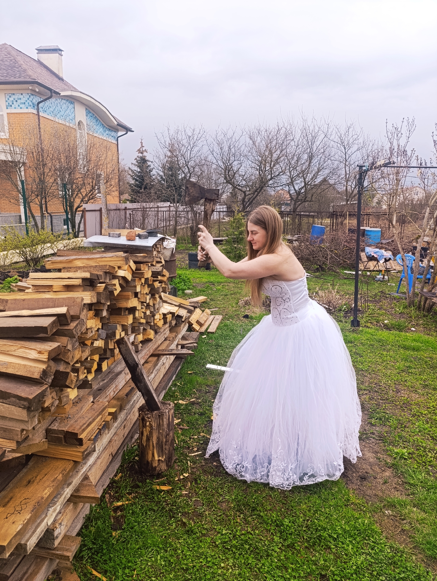 Bride splits wood with axe in backyard