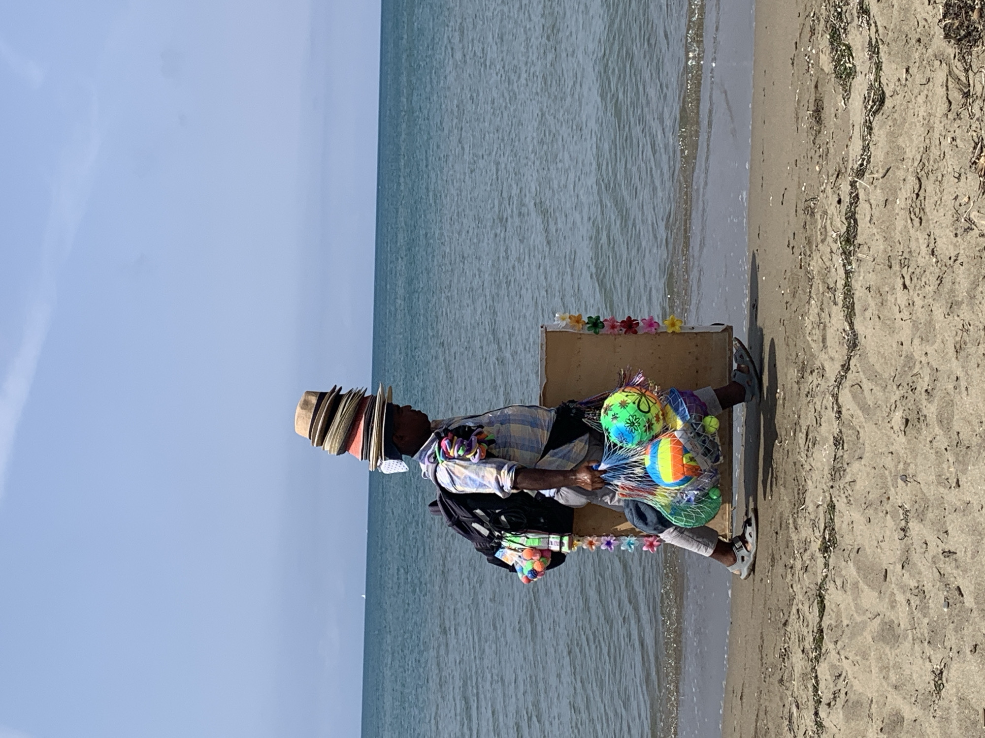 Hat vendor strolls Orbetello beach loaded up for business