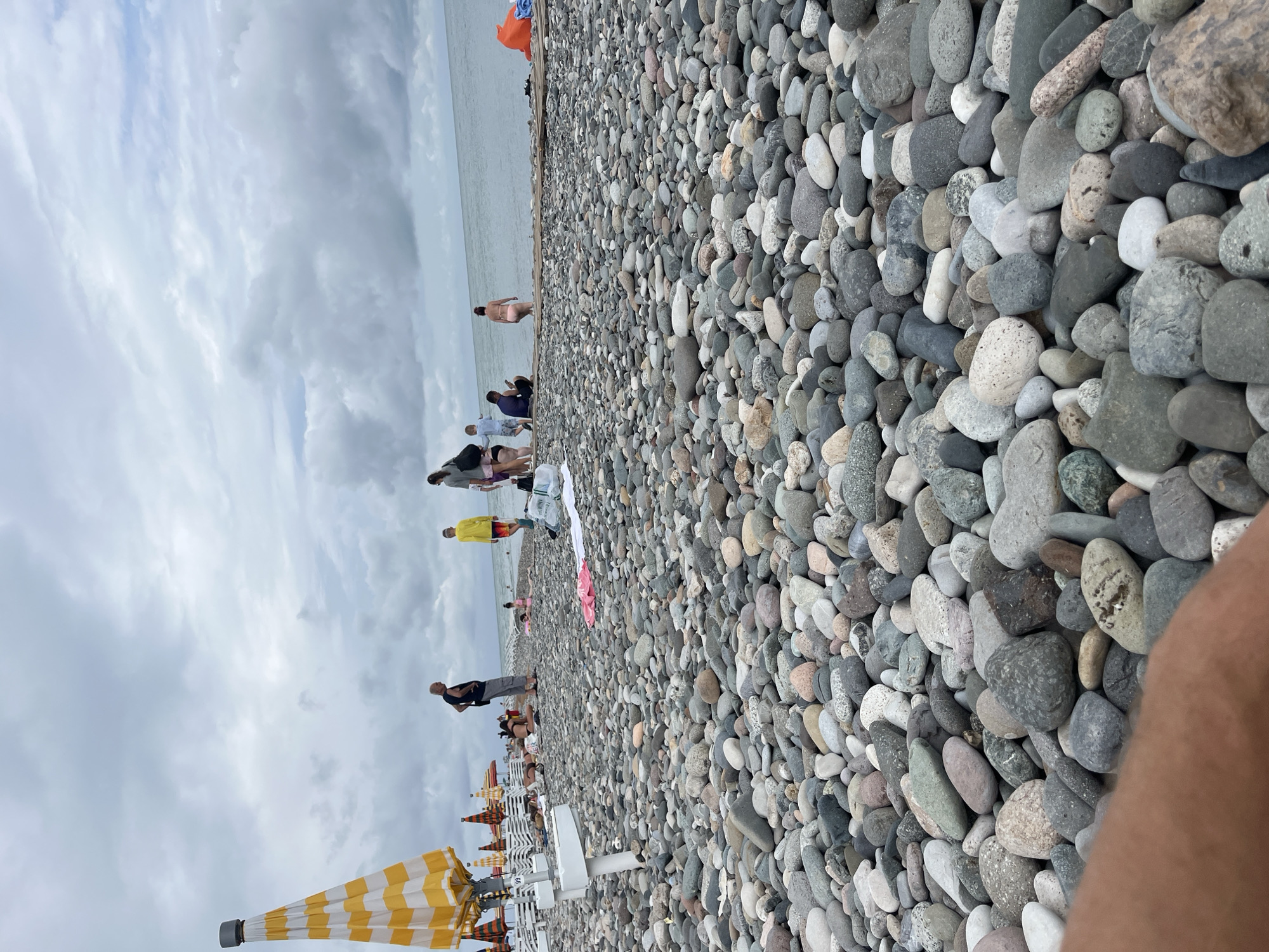 Busy morning on Batumi's pebble beach under cloudy skies