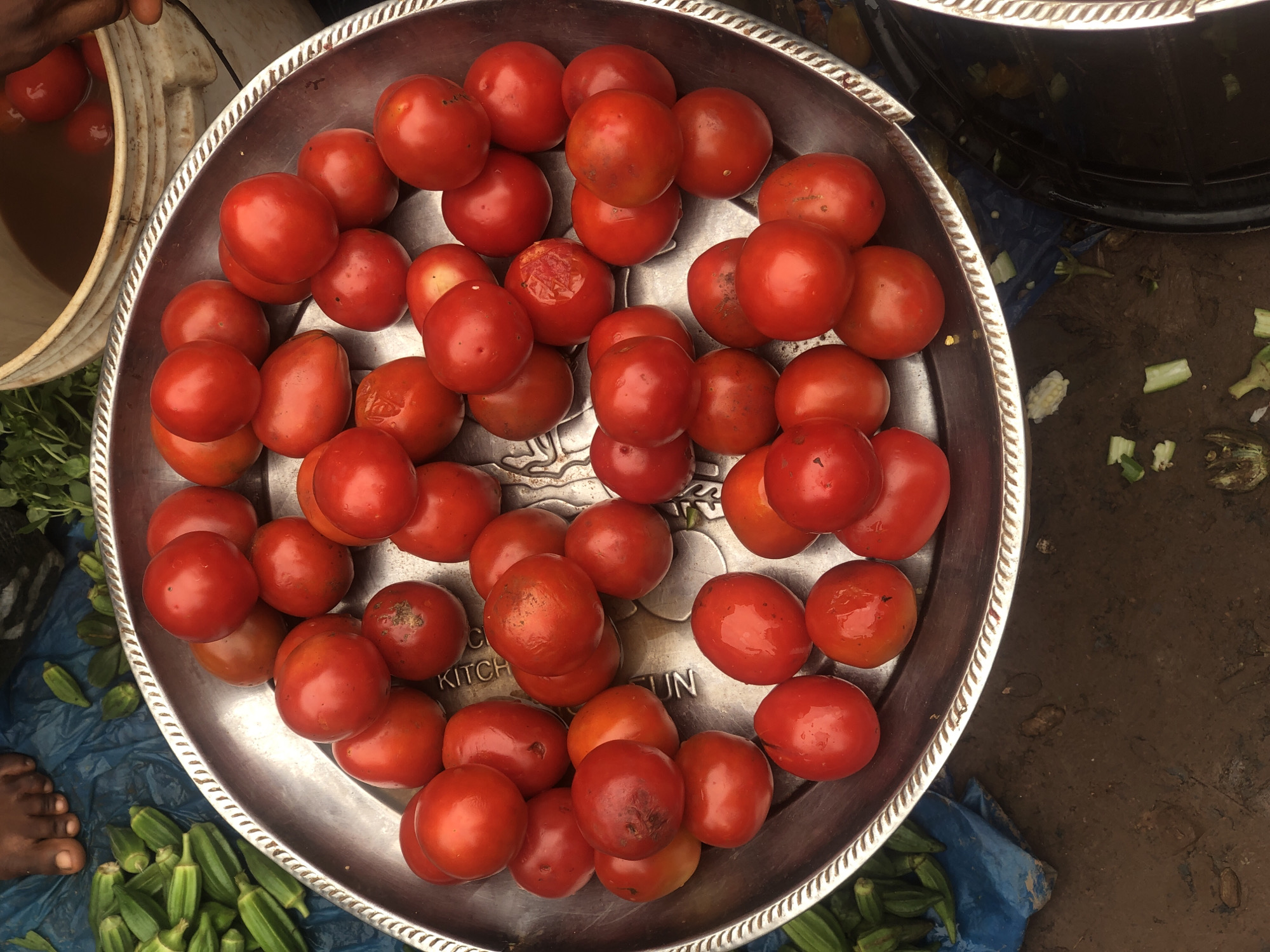 Tomatoes displayed in decorative tray on muddy ground in Abakaliki