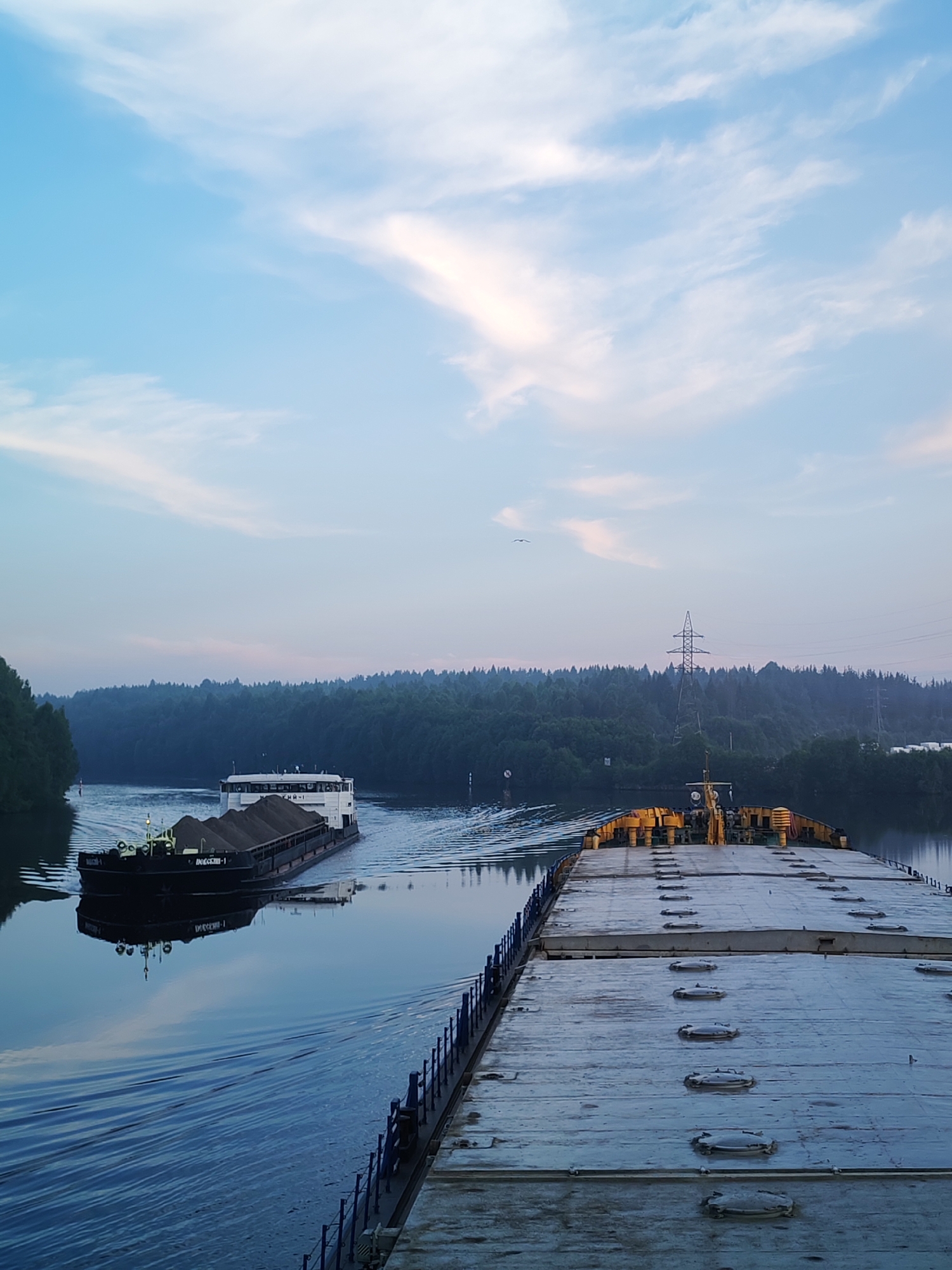 Barges hauling sand down a forested Russian river