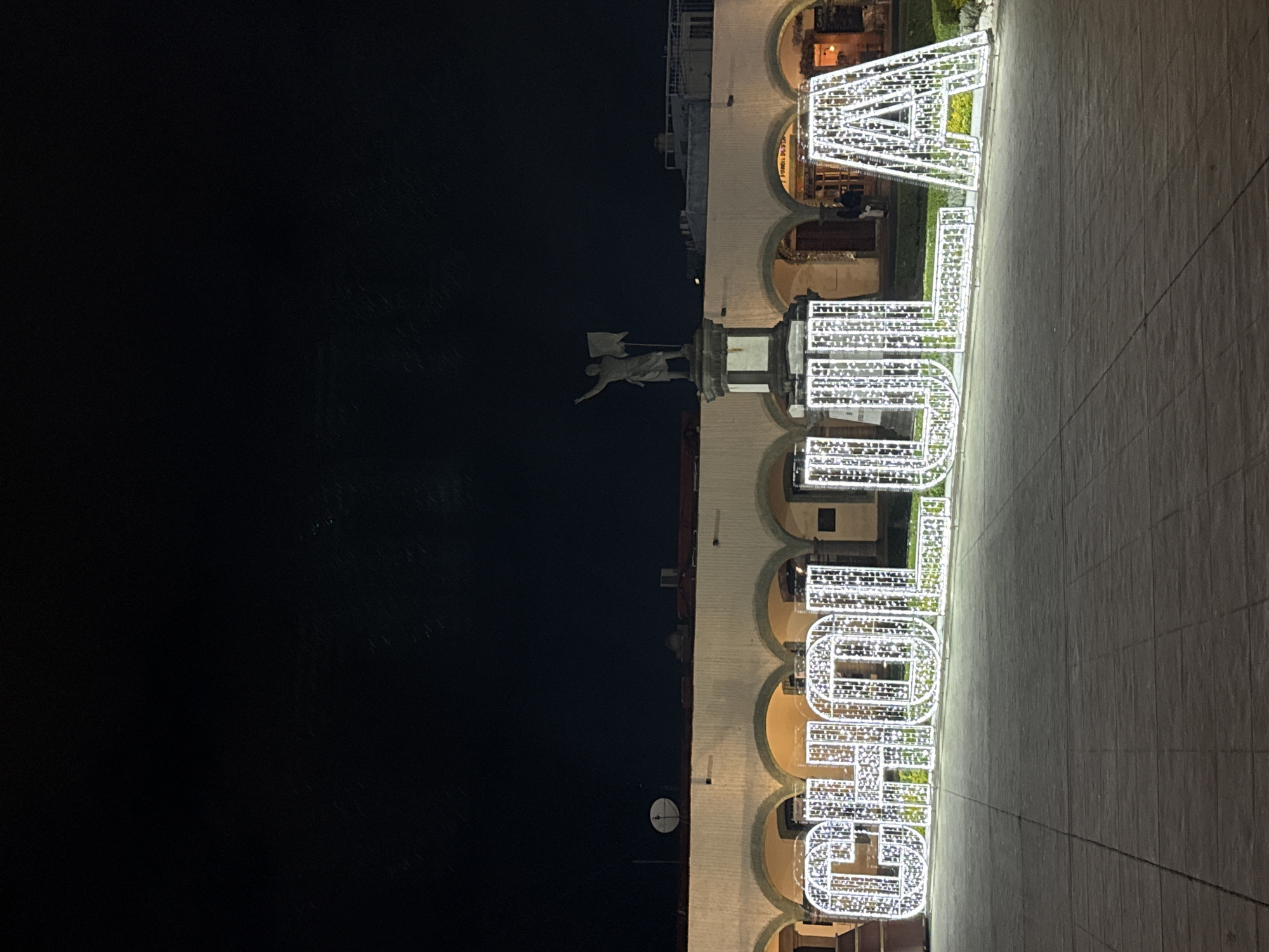 Illuminated Cholula sign glows beside municipal building at night