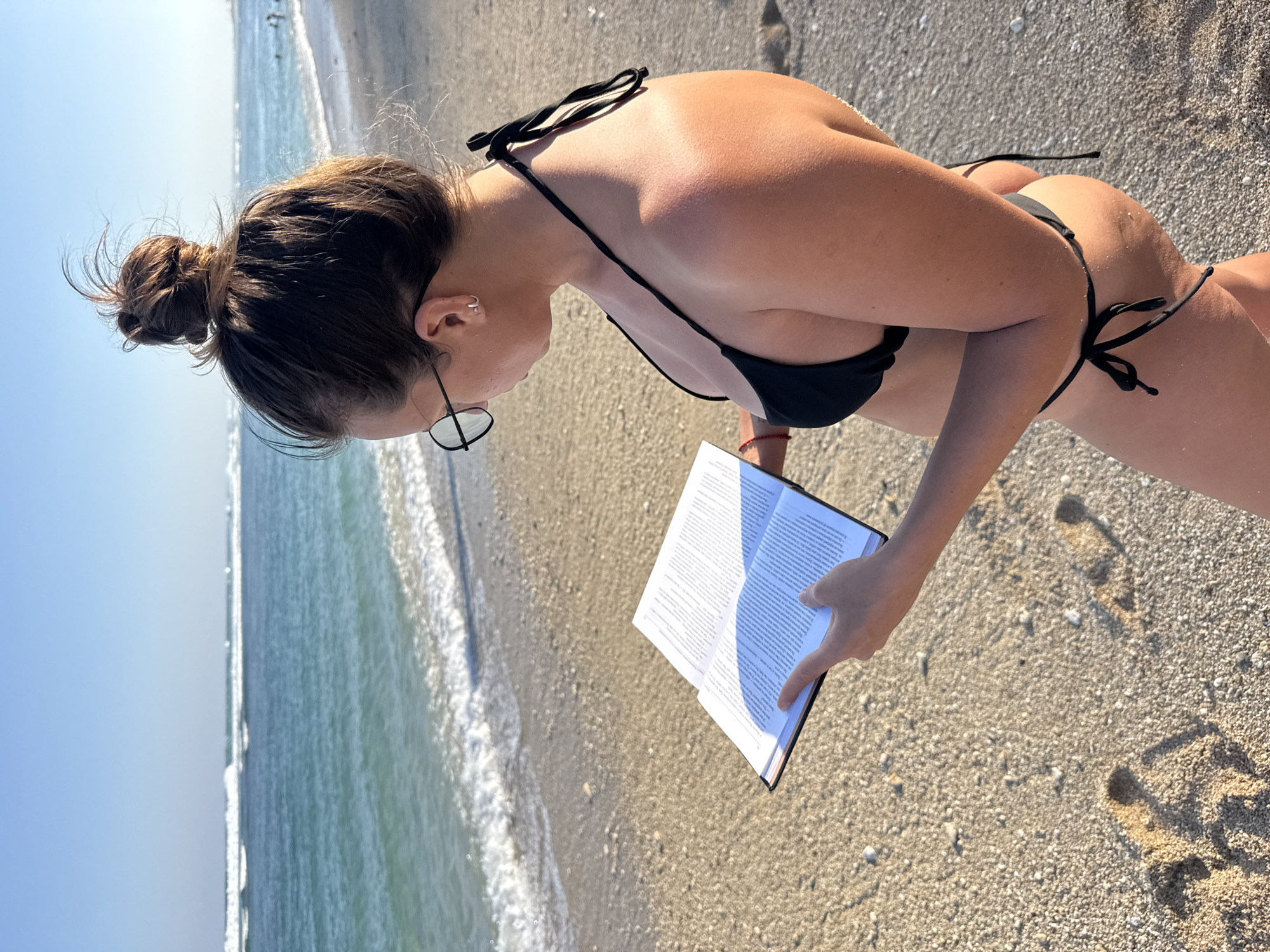 Woman reads book aloud on Indonesian beach morning