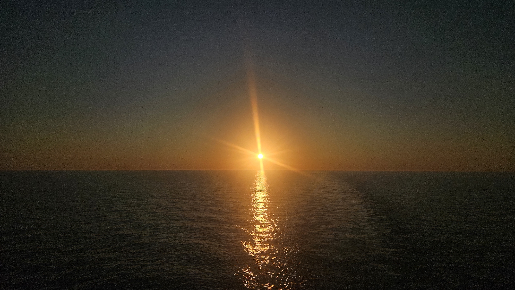 Sun hits the horizon over Swedish coastal waters at dusk.