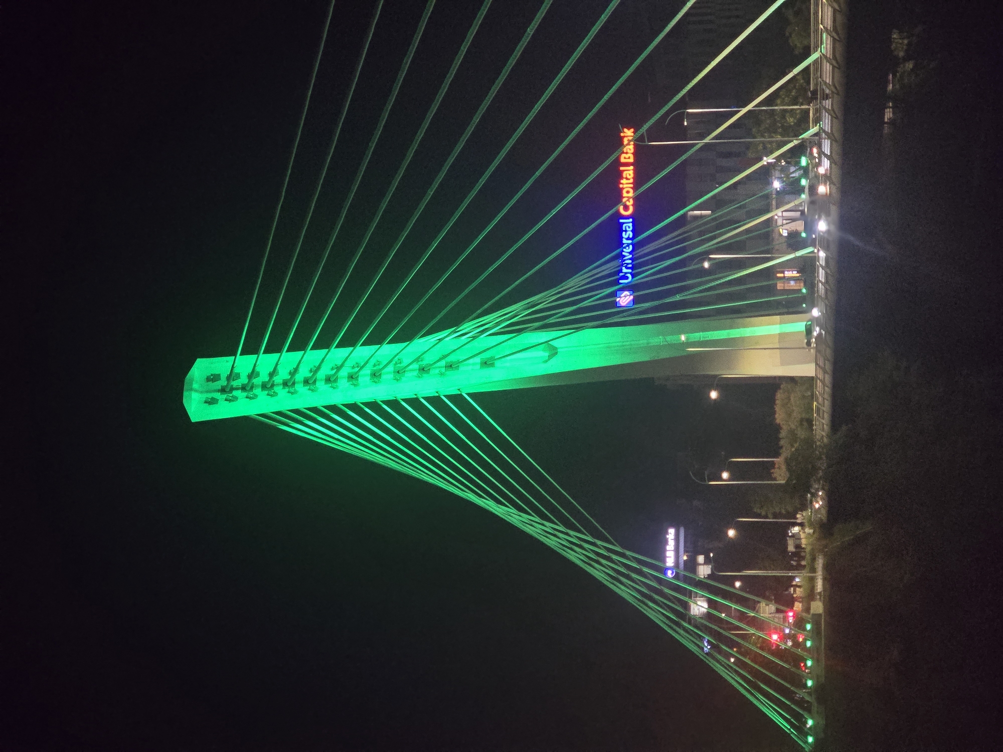 Green-lit cable-stayed bridge explored at night from multiple angles