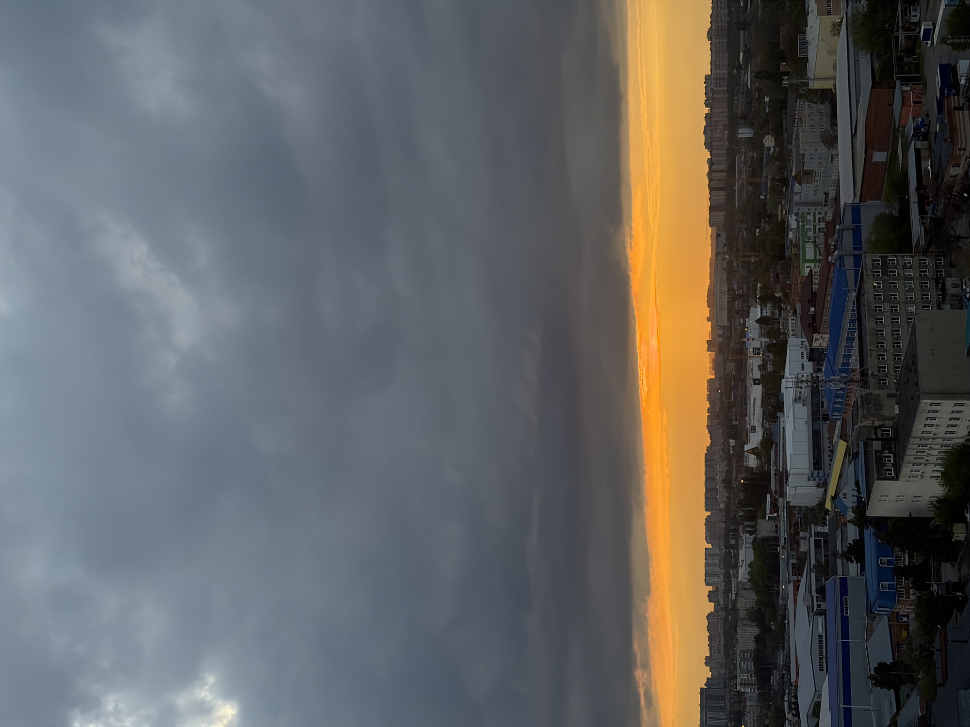 Dramatic storm clouds contrast golden light over Krasnodar cityscape
