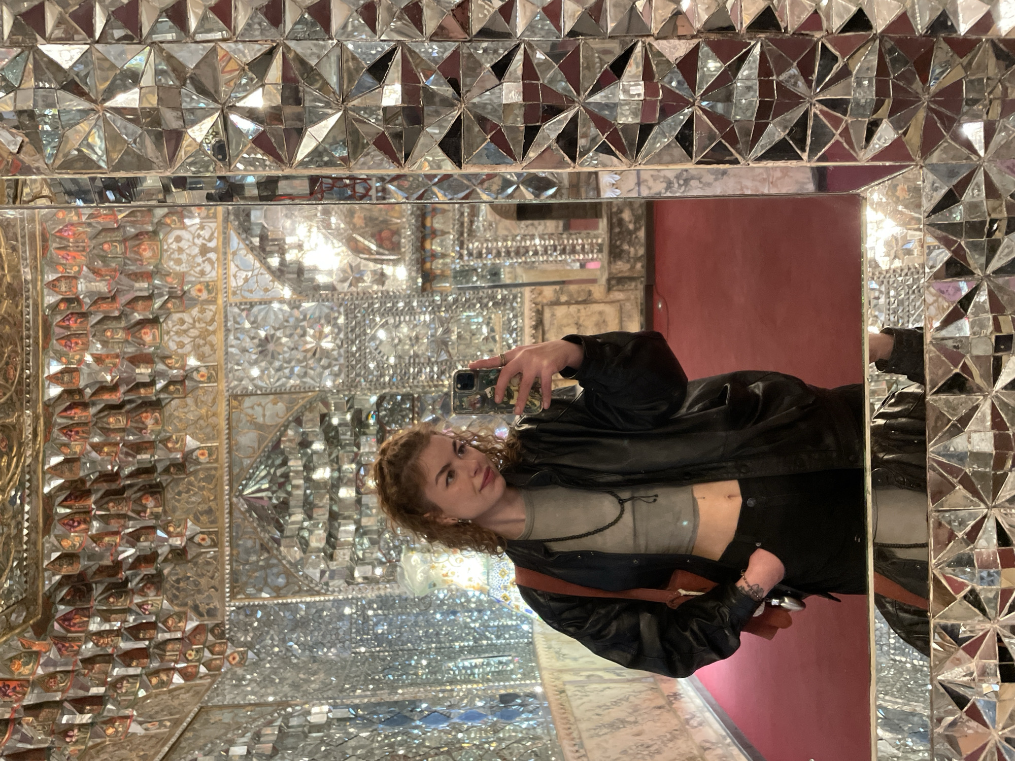 Woman takes mirror selfie in ornate kaleidoscopic room, Tbilisi