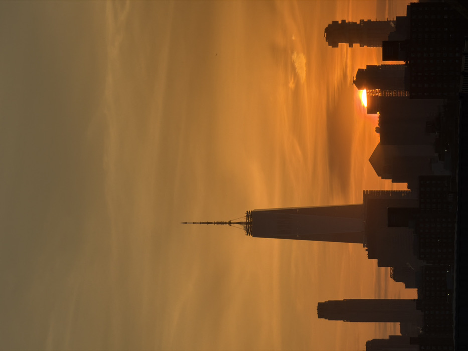Golden sunset silhouettes NYC skyline featuring One World Trade Center