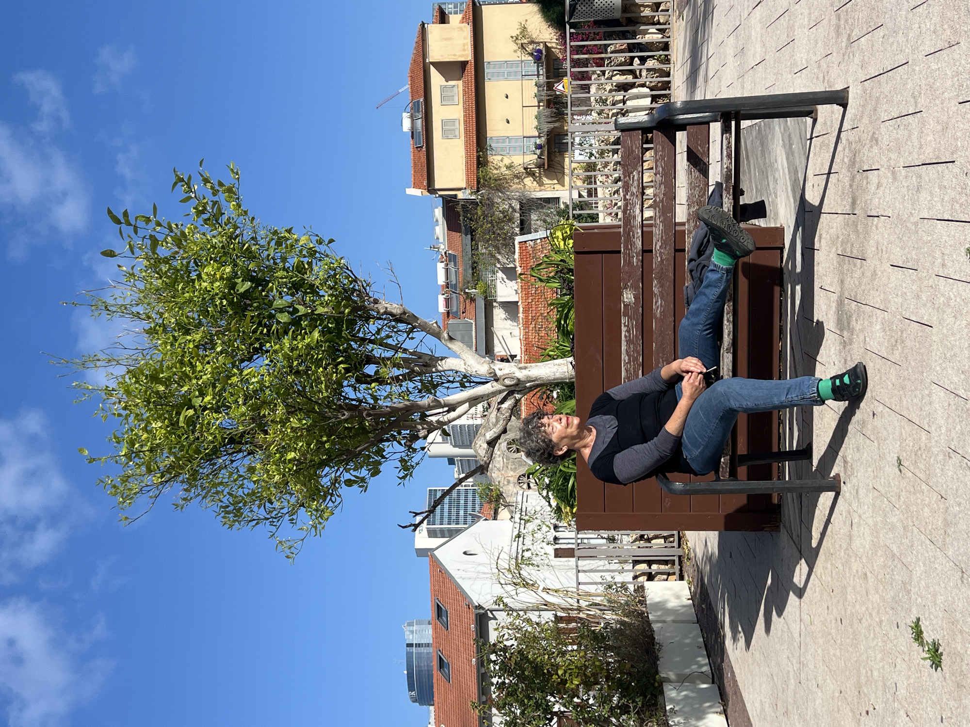 Woman relaxes with dog on Tel Aviv park bench