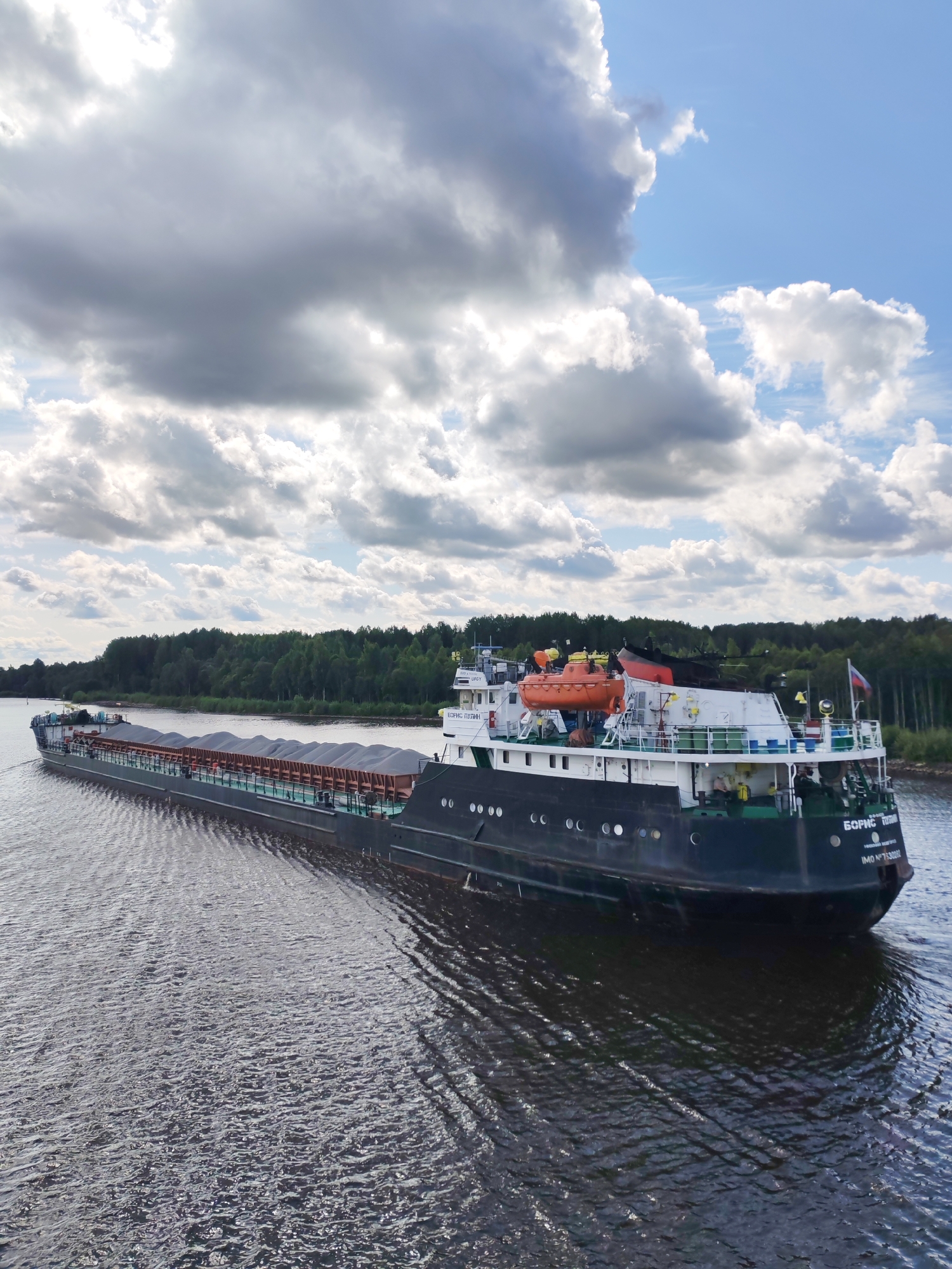 Cargo barges and a tanker move along a Russian river