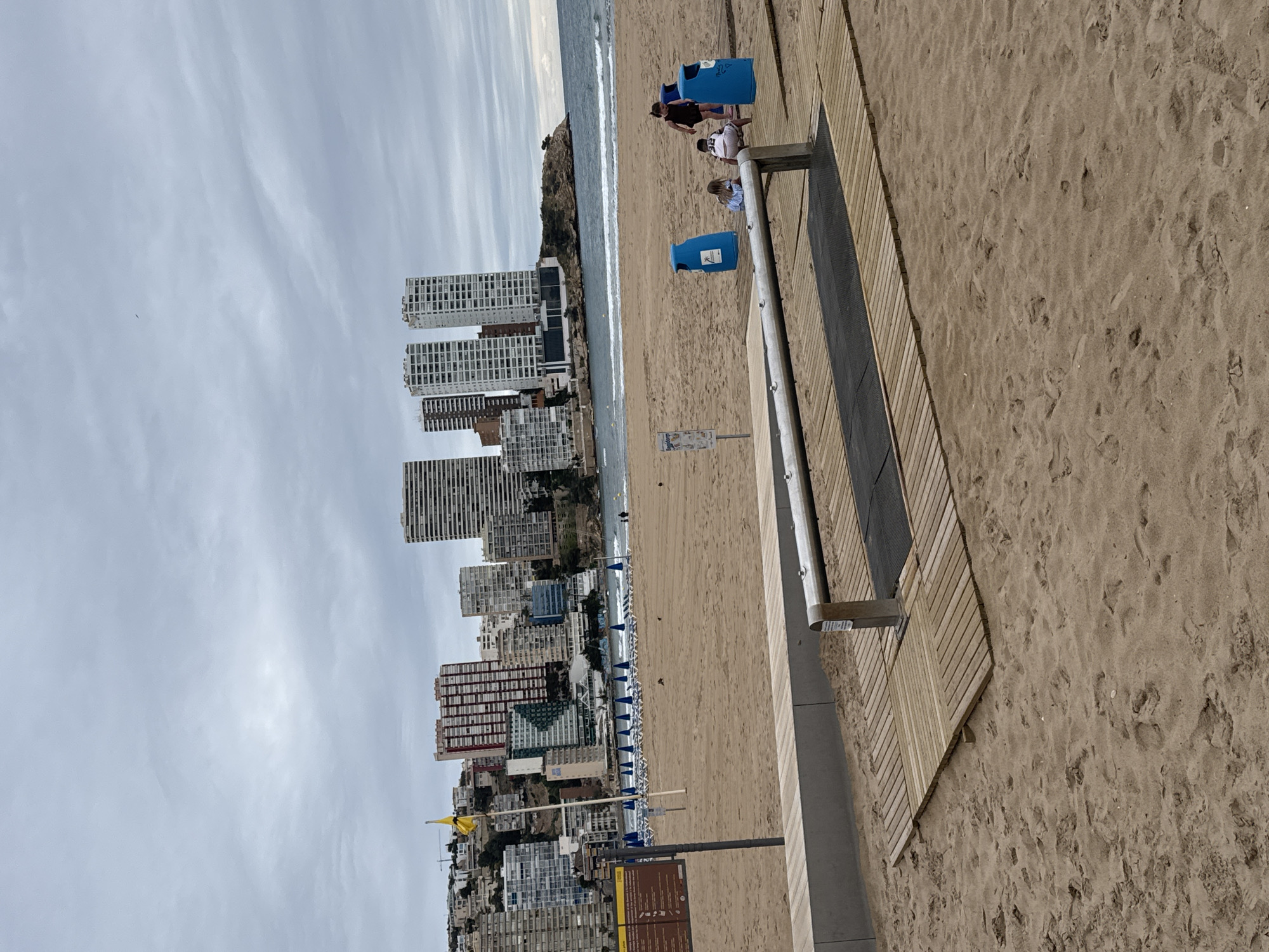Overcast afternoon documented at Benidorm beach with organized chair setup