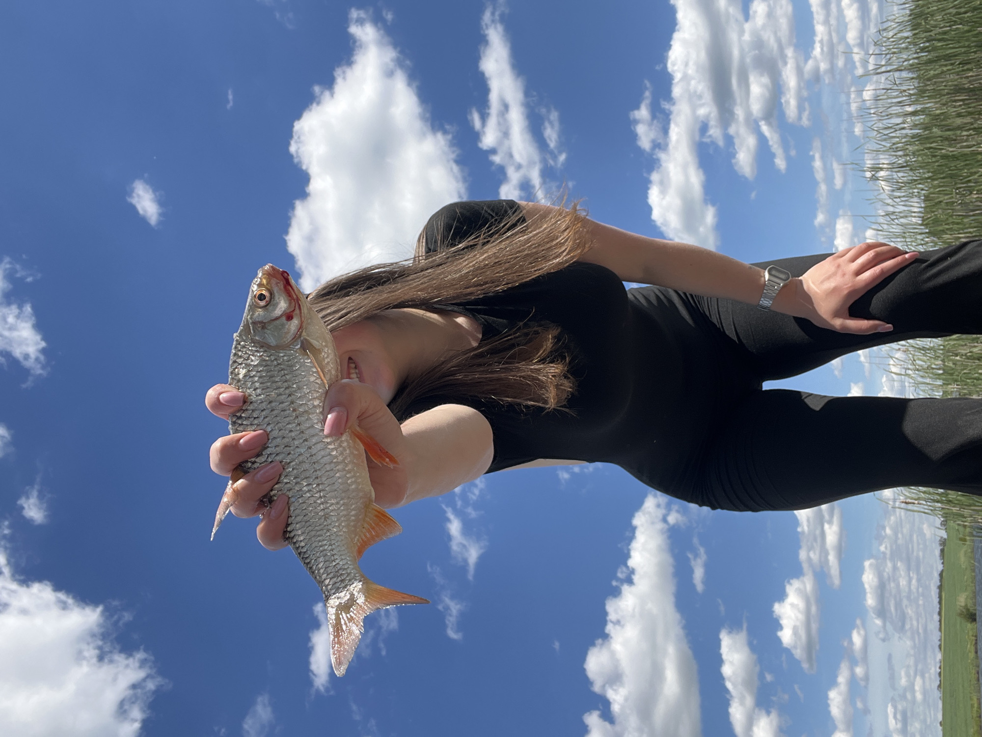 Person displays fish catch under blue skies in Rudky
