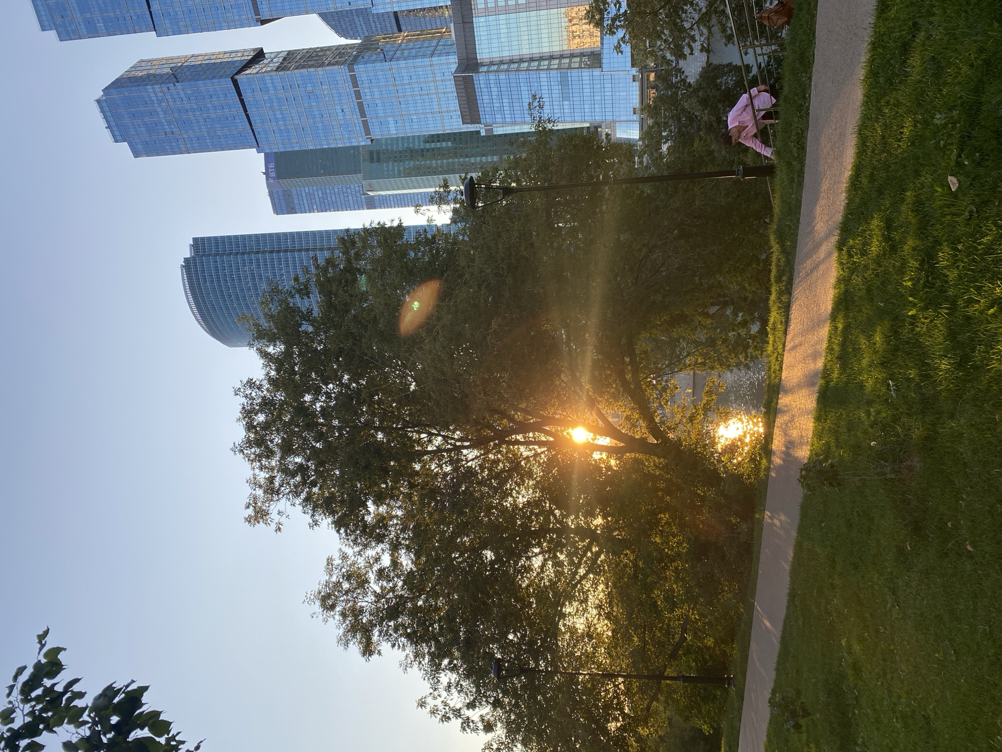 Sunset in a Moscow waterfront park beside glass skyscrapers