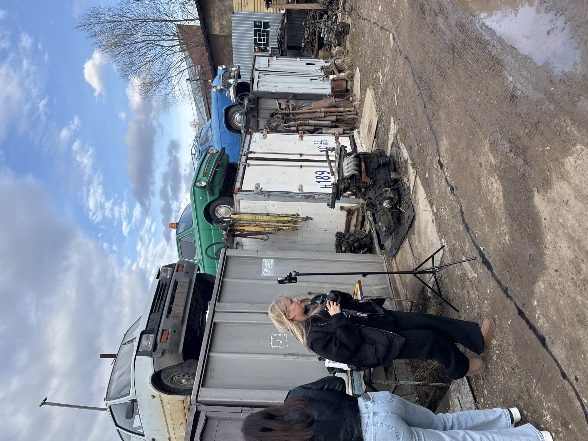 Young women film smartphone video at Russian auto junkyard