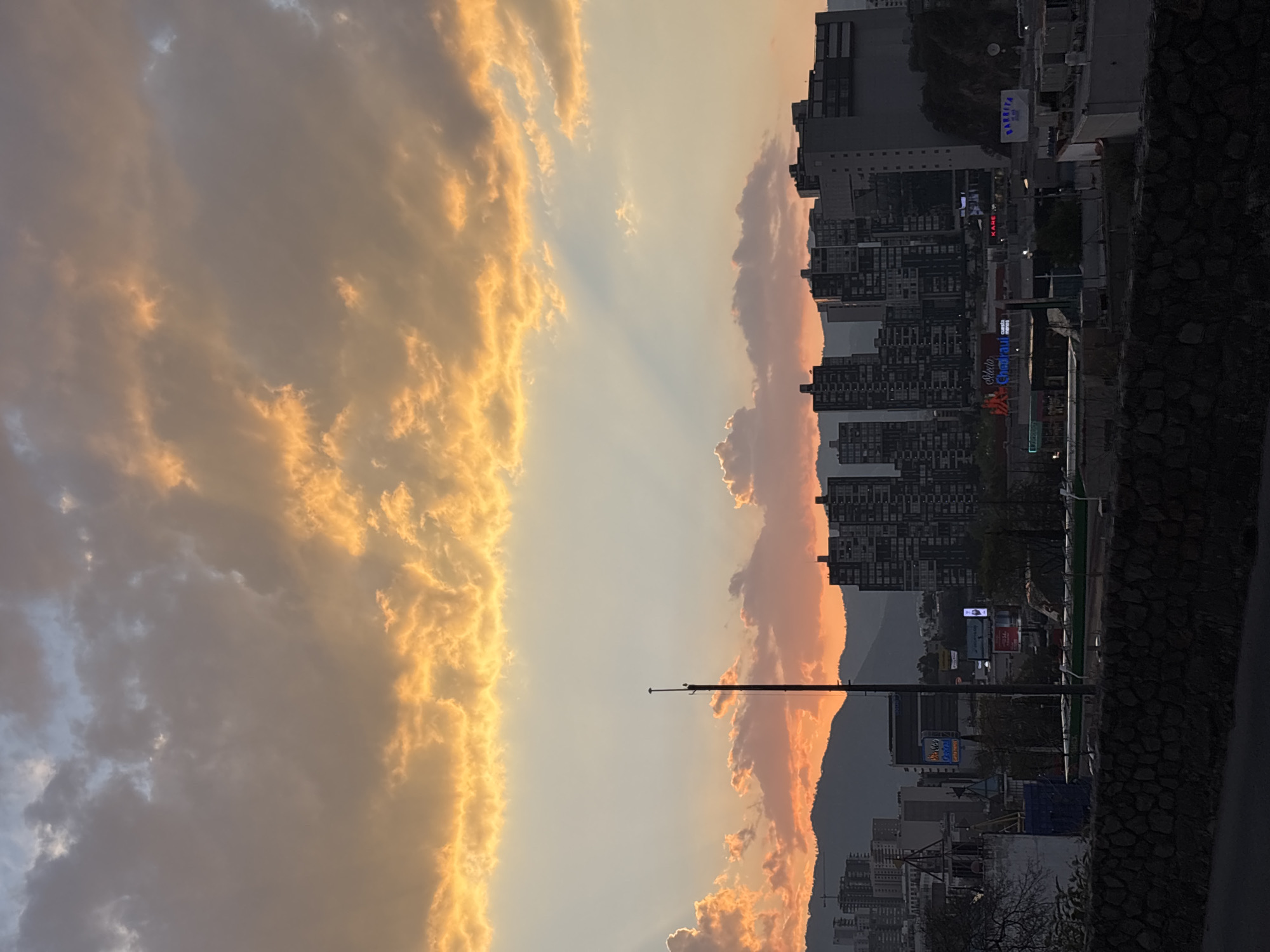 Sunset illuminates urban Huixquilucan skyline against mountain backdrop