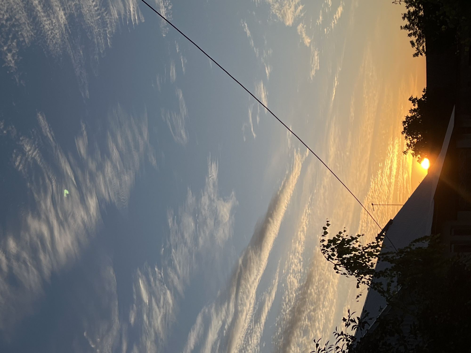 Slobozia sunset: blue sky, wispy clouds, and rooftop silhouettes