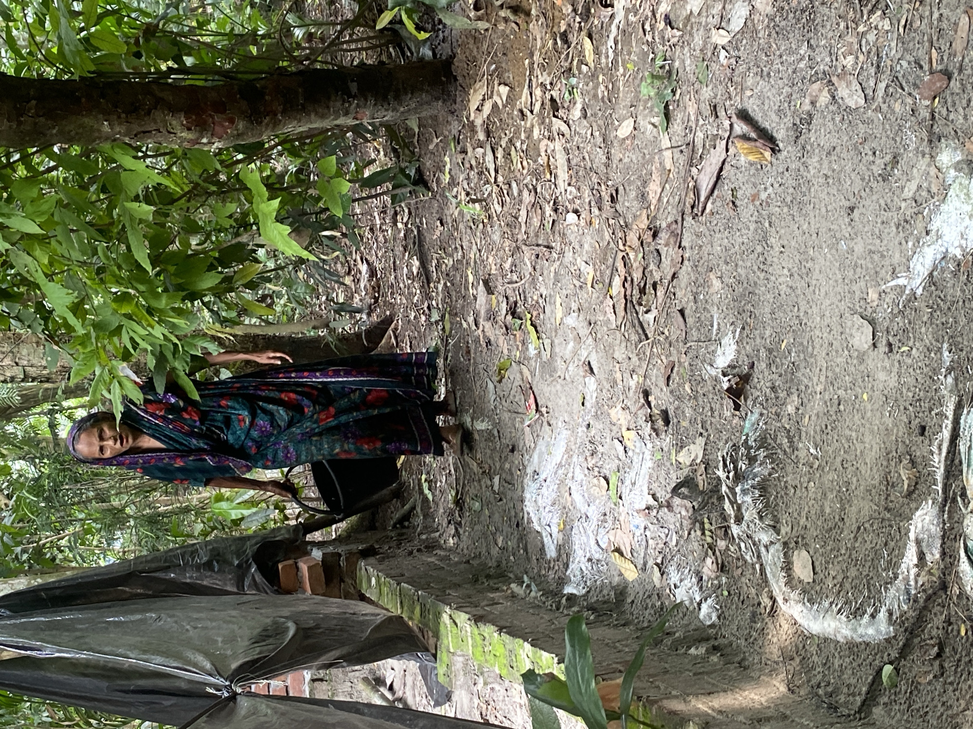 Woman in headscarf stands near brick structure in Bangladesh