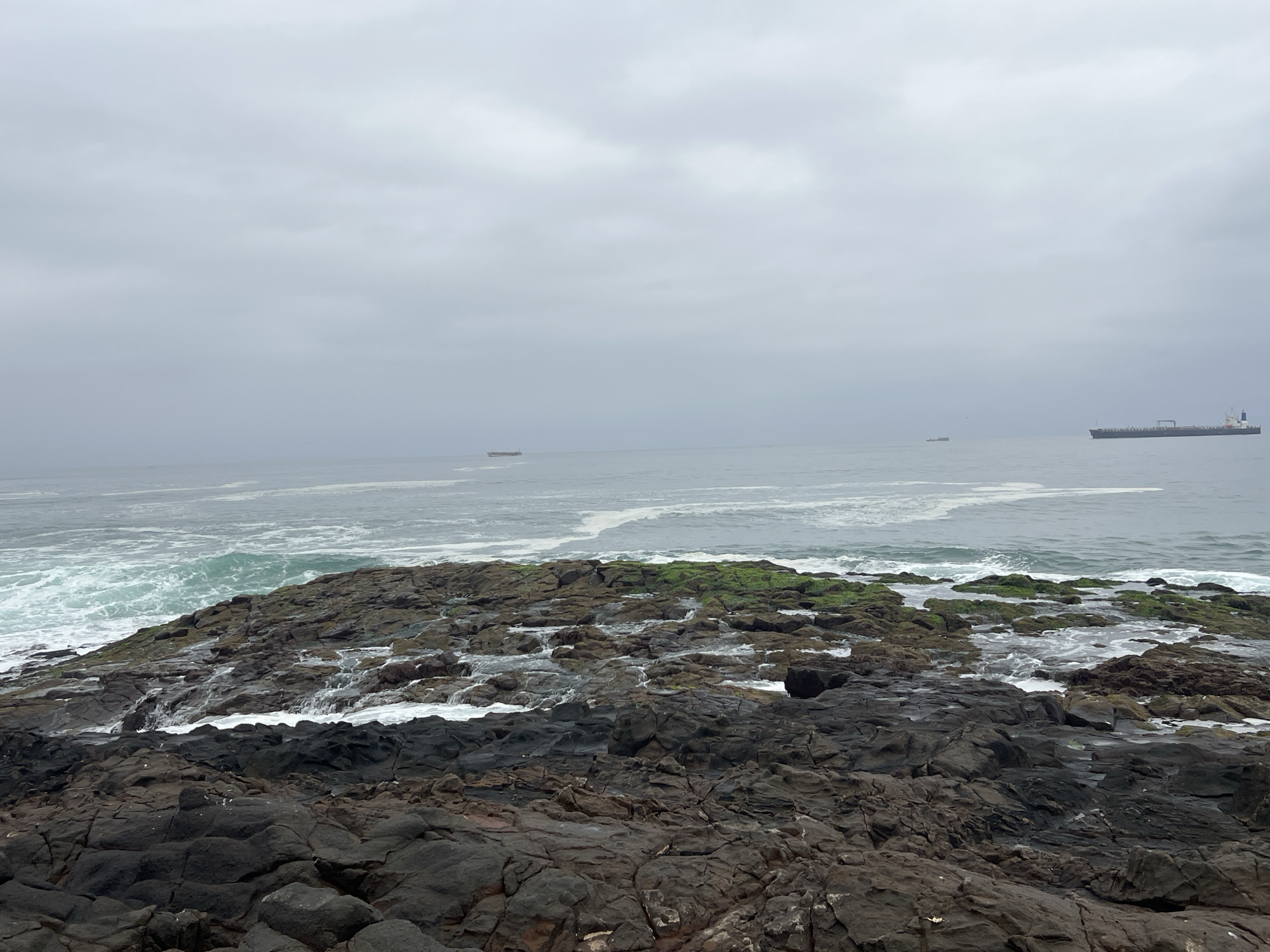 Surfers work choppy waves off Arica's rocky Pacific shore.